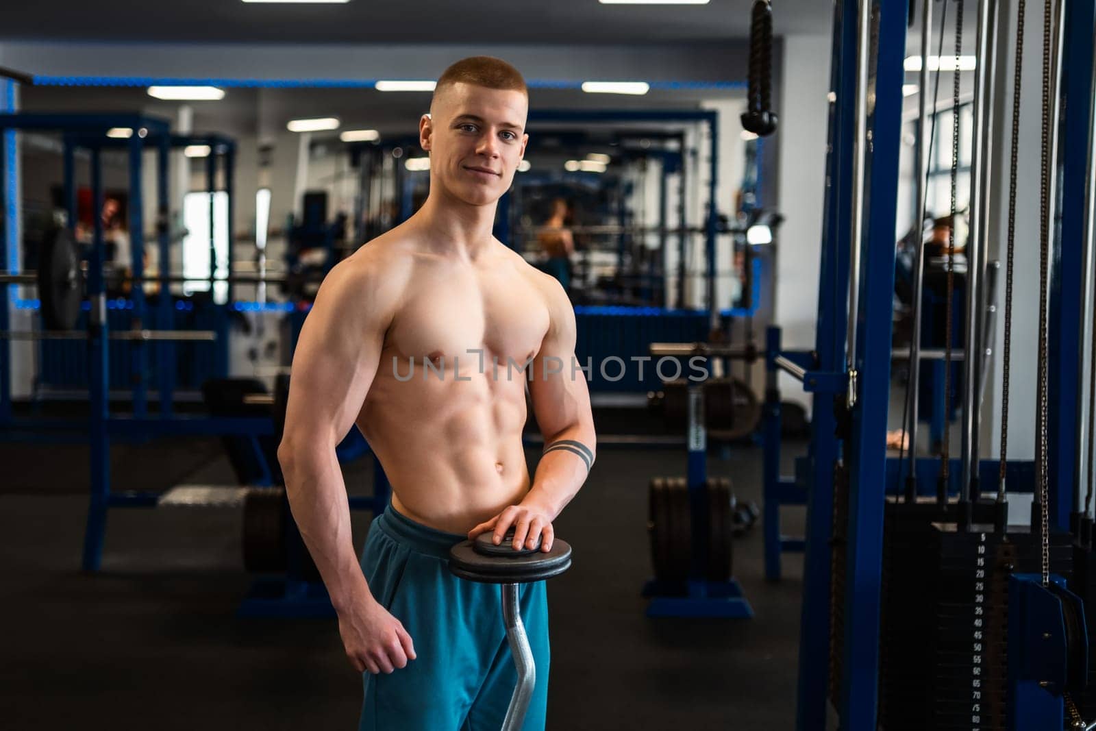 Portrait of muscular bodybuilder holding a barbell standing in the fitness center.
