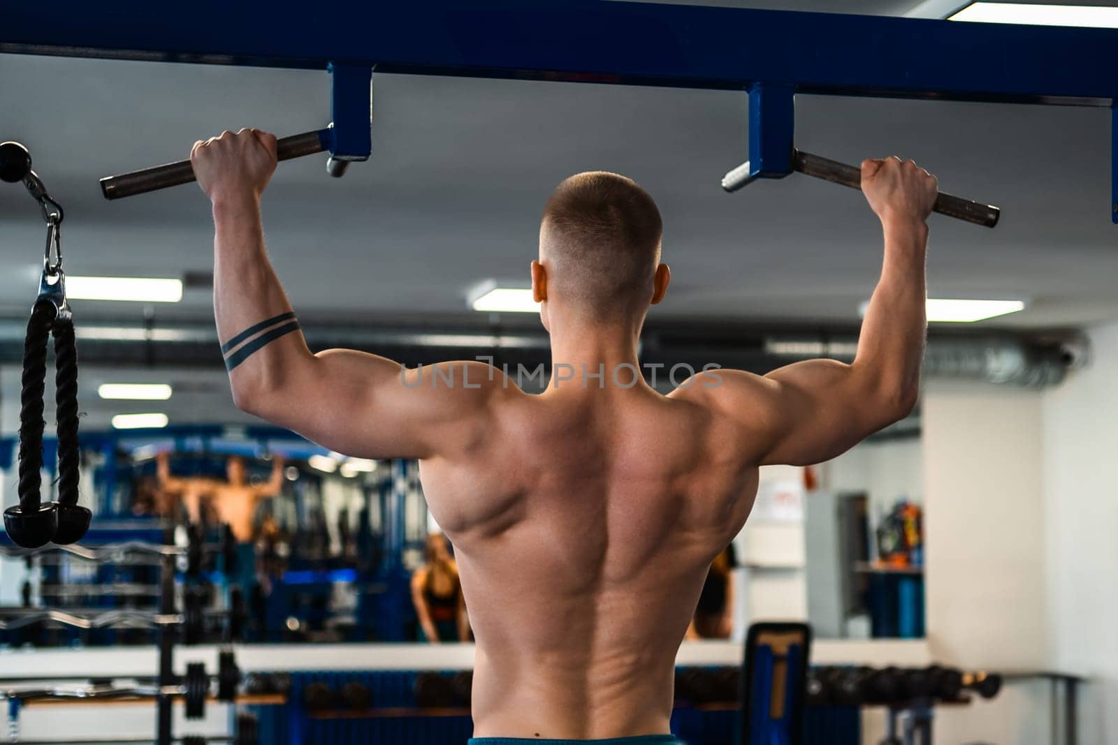 Bodybuilder doing pull-ups in a gym.