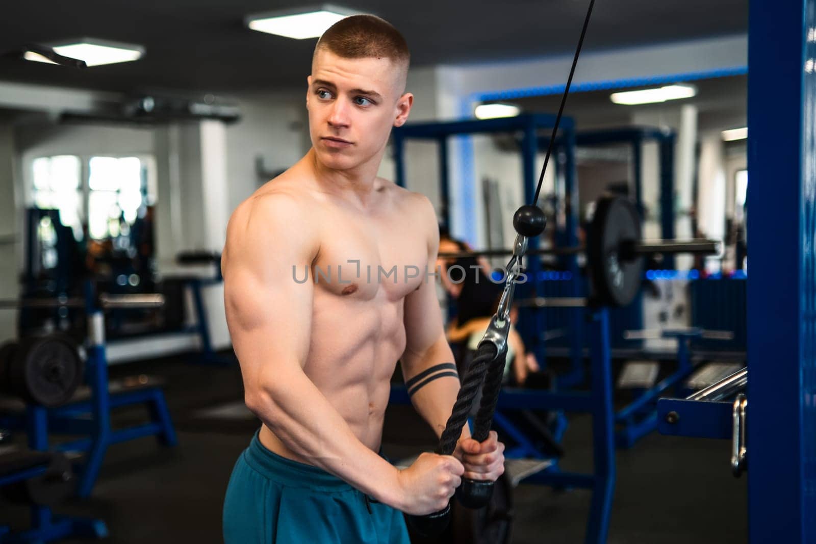A young man works out on a cable machine in a gym