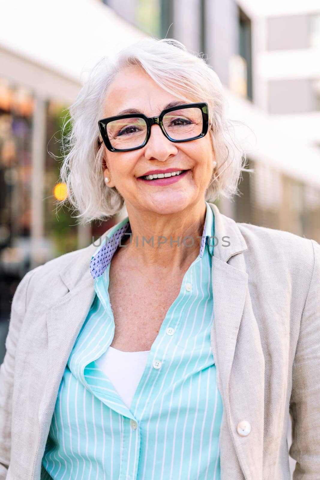 portrait of a stylish mature woman smiling happy looking at camera outdoors, concept of urban lifestyle in adulthood