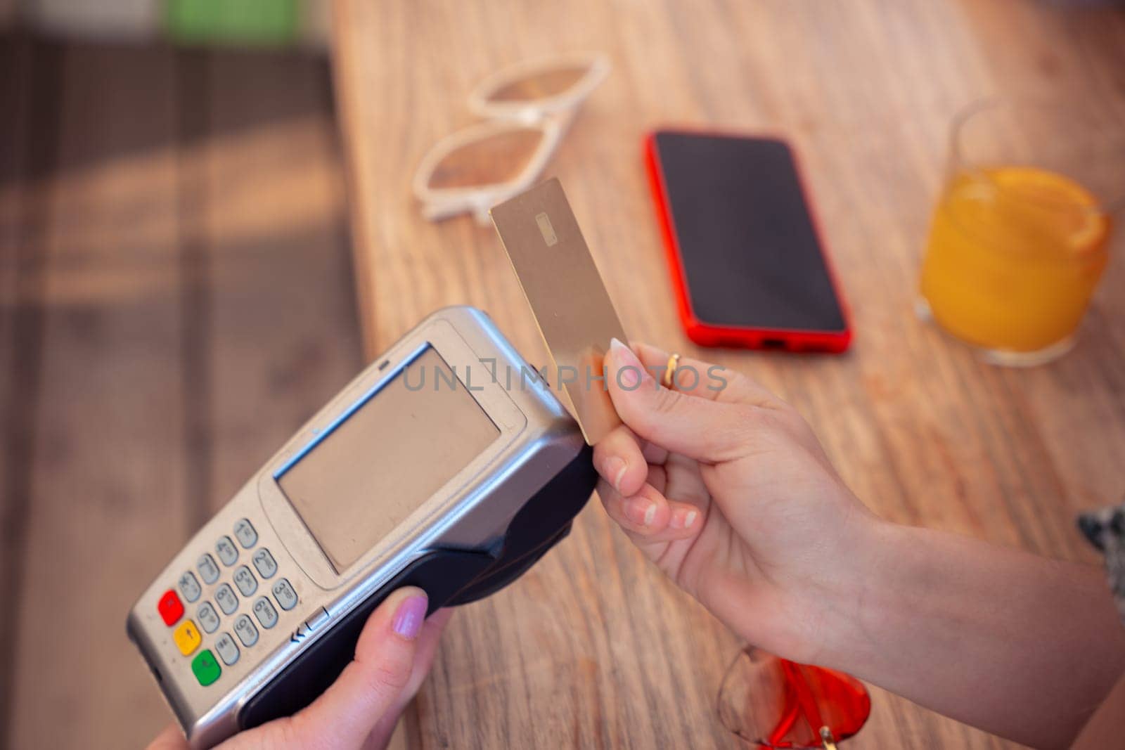 Unrecognizable Hand of a young woman holding a credit card and making a payment transaction.