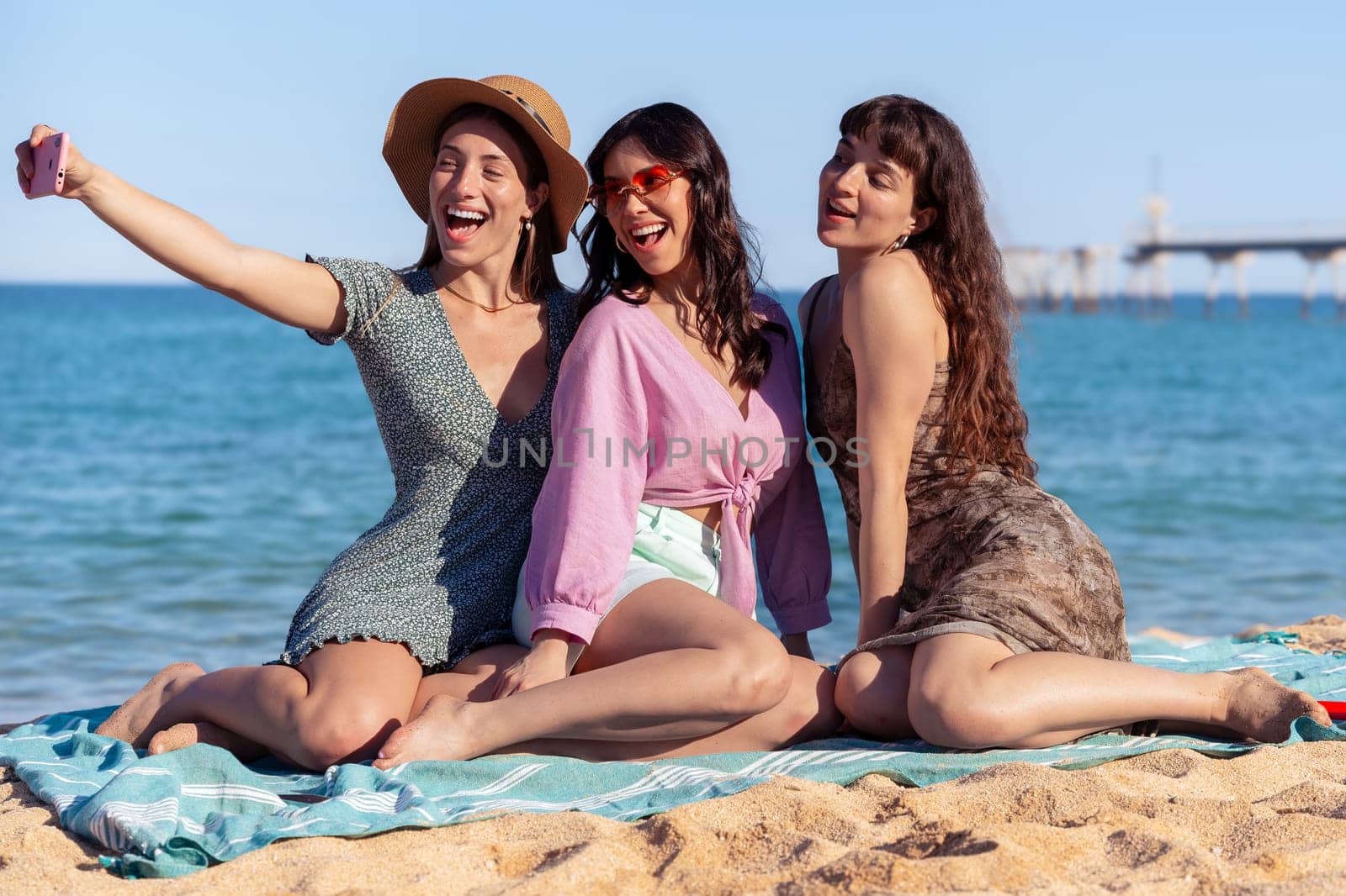 Group of smiling multiethnic women enjoying vacation. Beautiful and cheerful girls of generation z pose for a photo with a mobile phone.