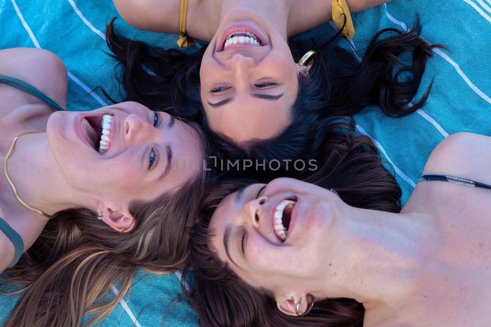 Group of girls on the beach wearing sunglasses lying on their backs on their summer vacation