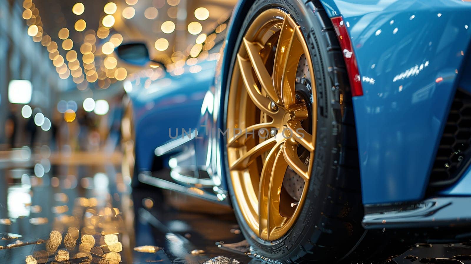 A close-up shot of a blue sports car with gold wheels, parked at an auto show. The car is illuminated by the bright lights of the event, creating a reflective surface.
