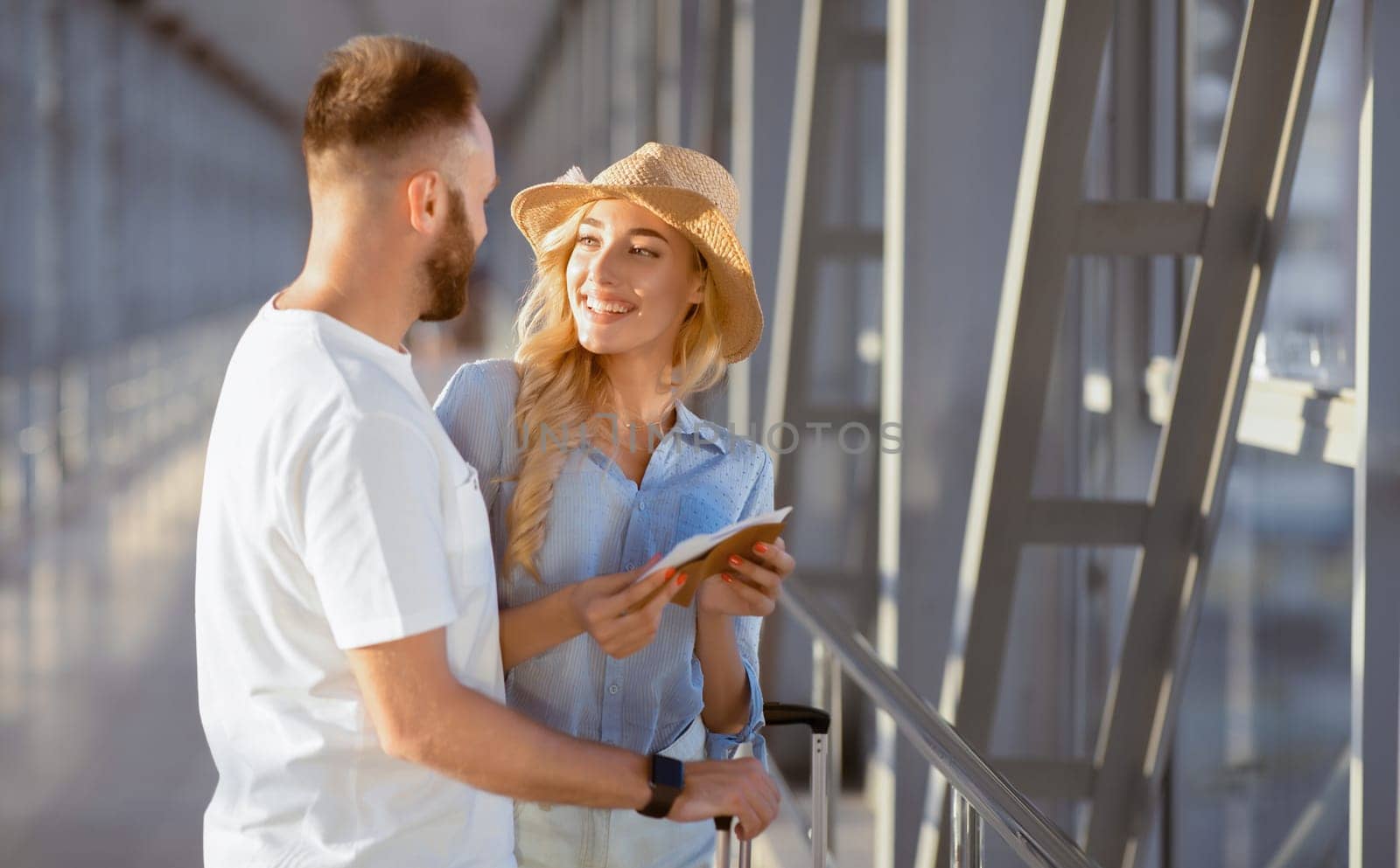 Traveling Concept. Portrait of lovely couple looking at each other standing in terminal and holding tickets
