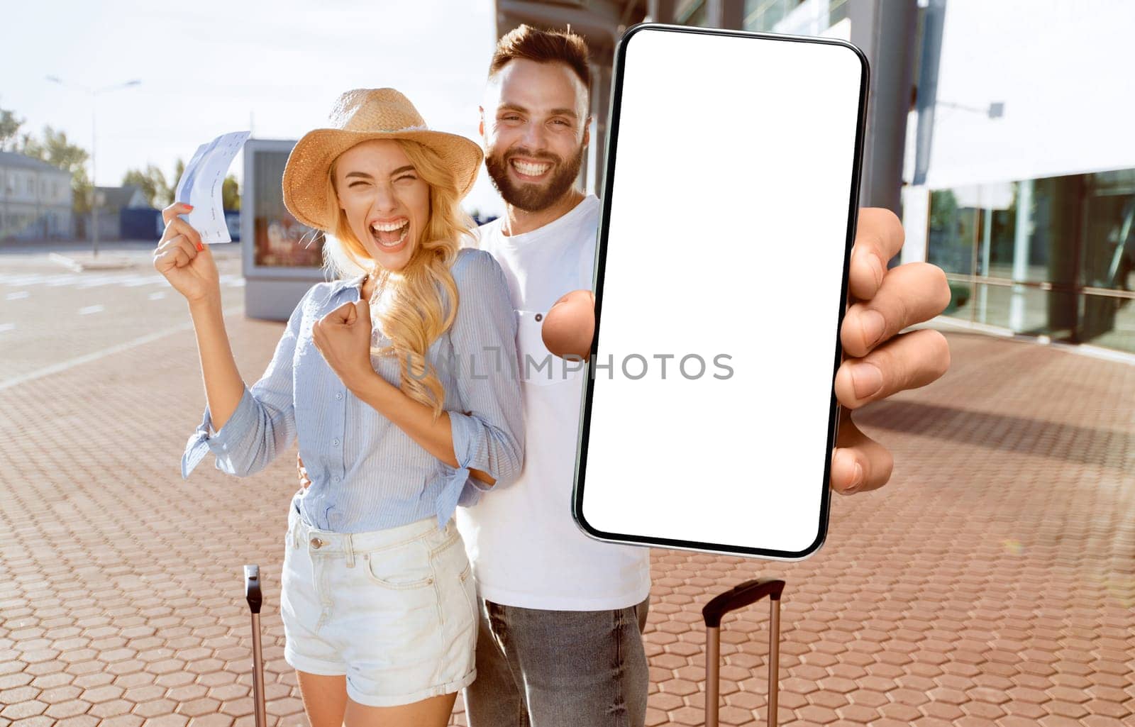 Ready For Vacation. Excited spouses with suitcases showing boarding passes and passports, standing near airport