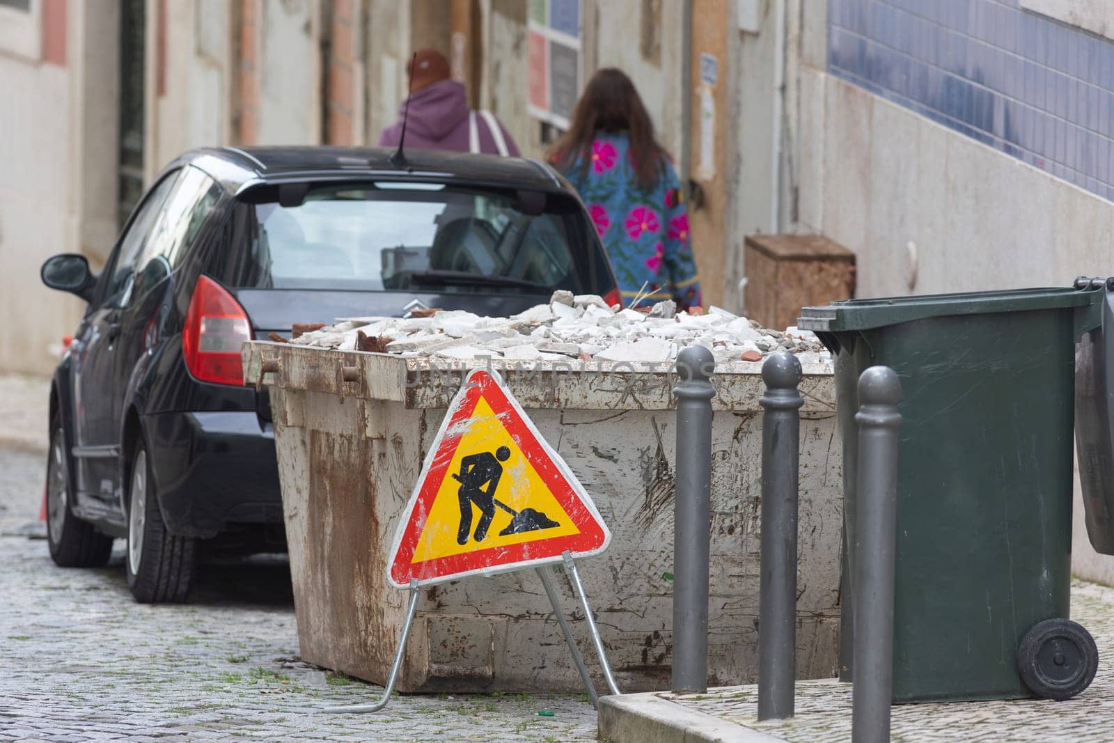 Construction trash container on the street next to the street sign
