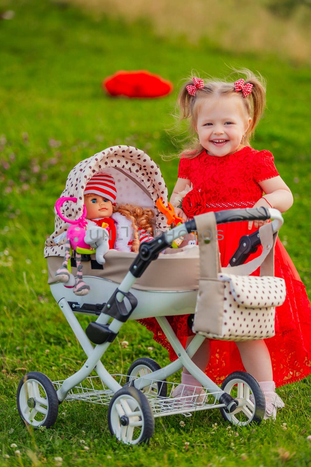 a child with a toy stroller and a doll is playing in nature