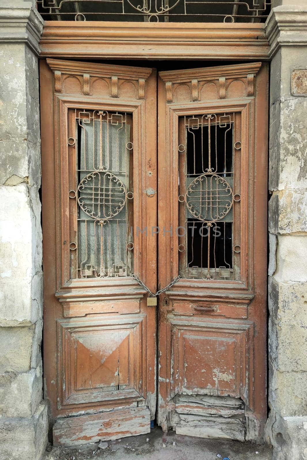 old entrance wooden double-leaf brown door with wrought iron decor and glass.