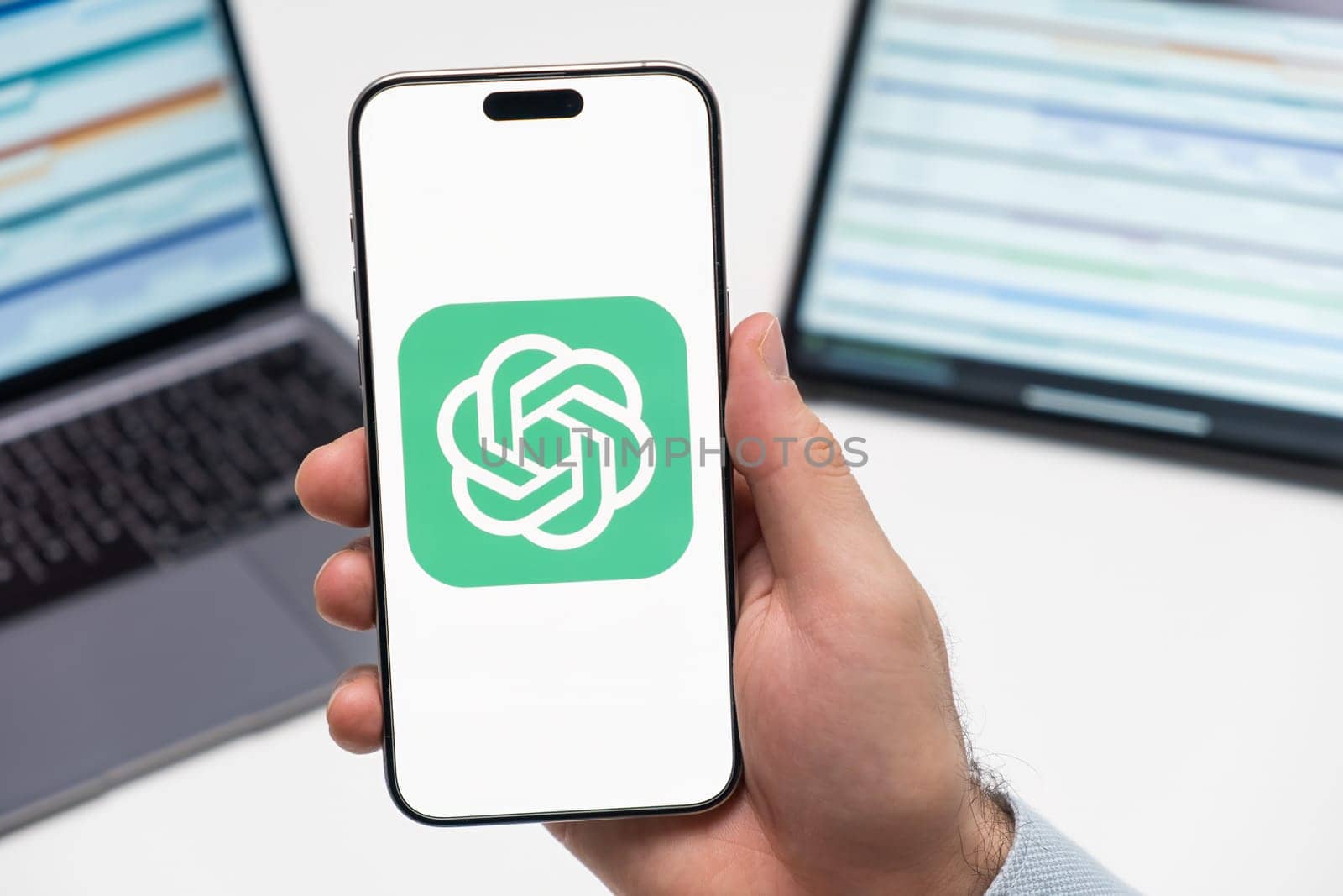 PRAGUE, CZECH REPUBLIC - JANUARY 21 2024: ChatGPT Open AI logo on the screen of smartphone in mans hand on the workplace background.