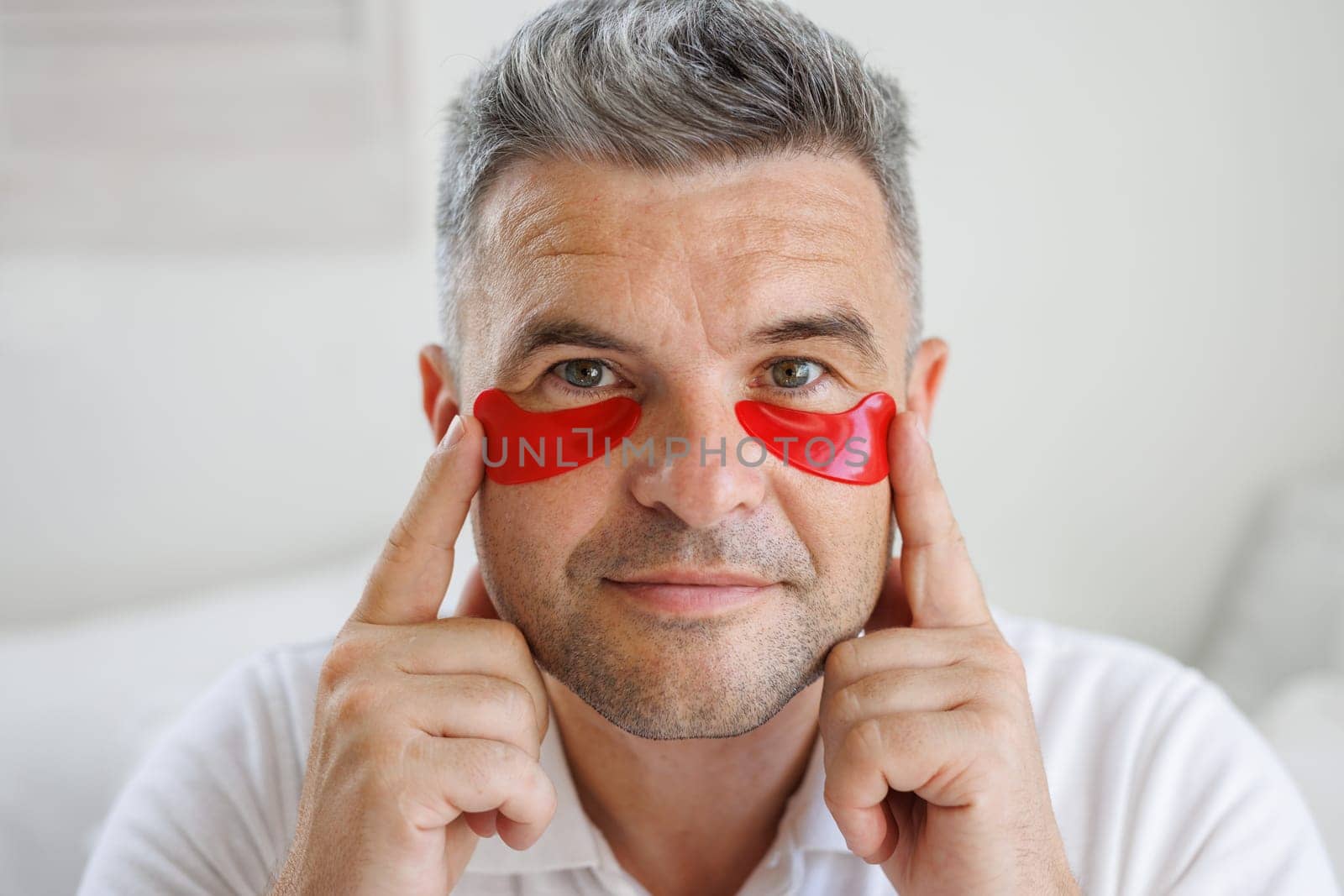 a man applies moisturizing patches with vitamins under his eyes, a modern cosmetic product for the eyes to smooth out fine wrinkles and remove redness