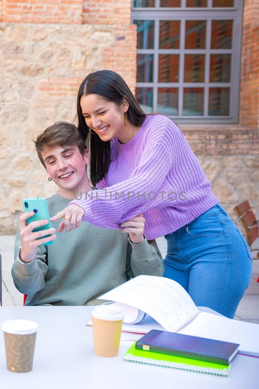 smiling multiracial students sitting outdoors using cell phone to chat online. University life concept