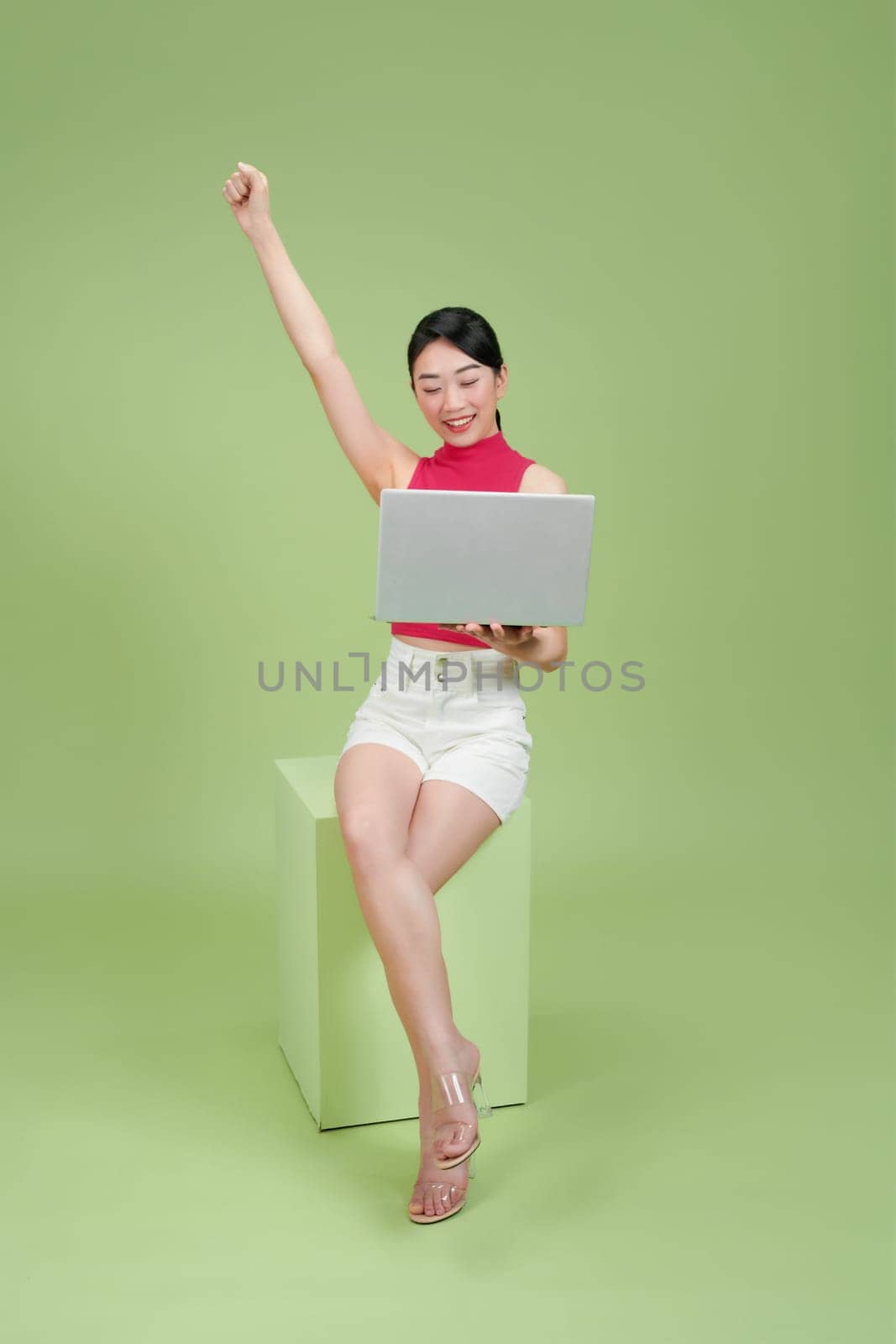 A joyful woman celebrating success while working on her laptop