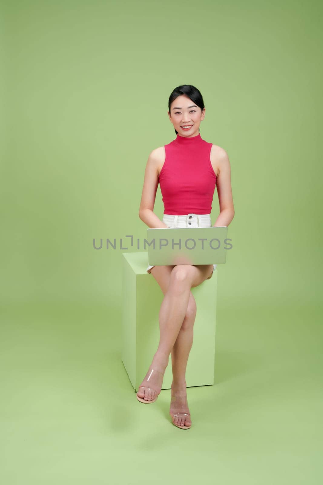 Young Woman Working on Laptop Against Green Background