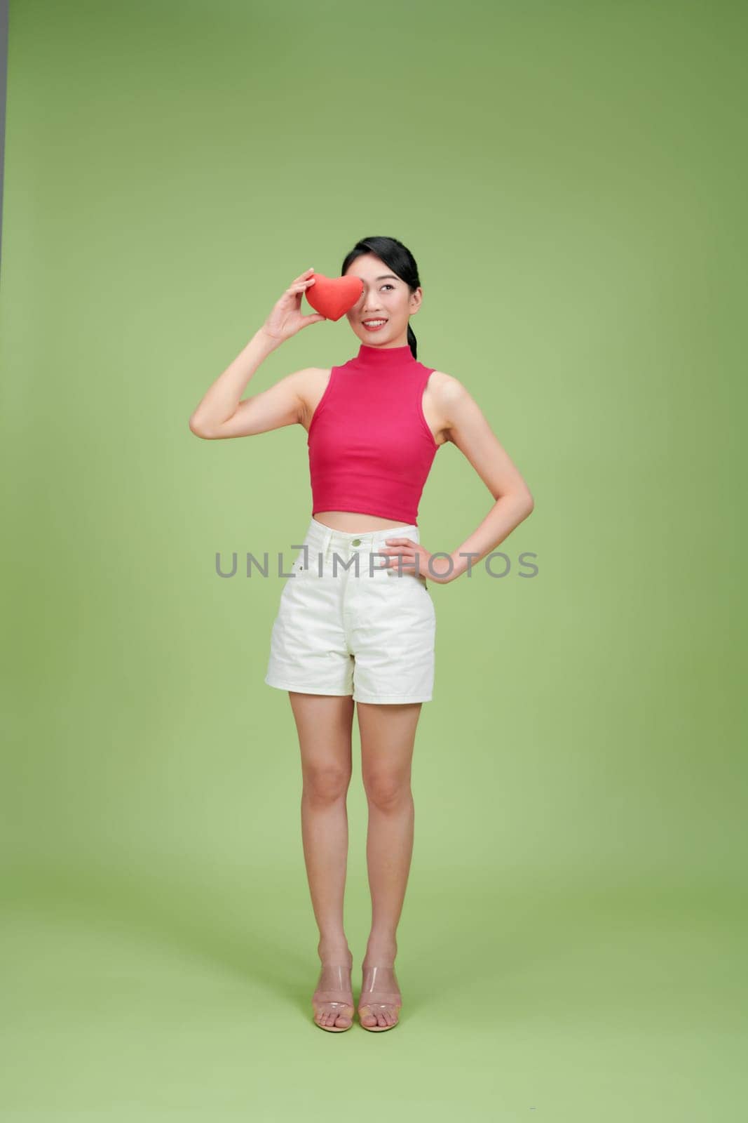 Beautiful woman hold red heart, isolated on green background