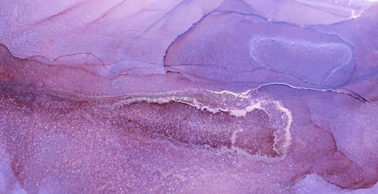 A close-up of an abstract painting featuring swirling patterns of purple and silver ink, creating a fluid and ethereal effect.