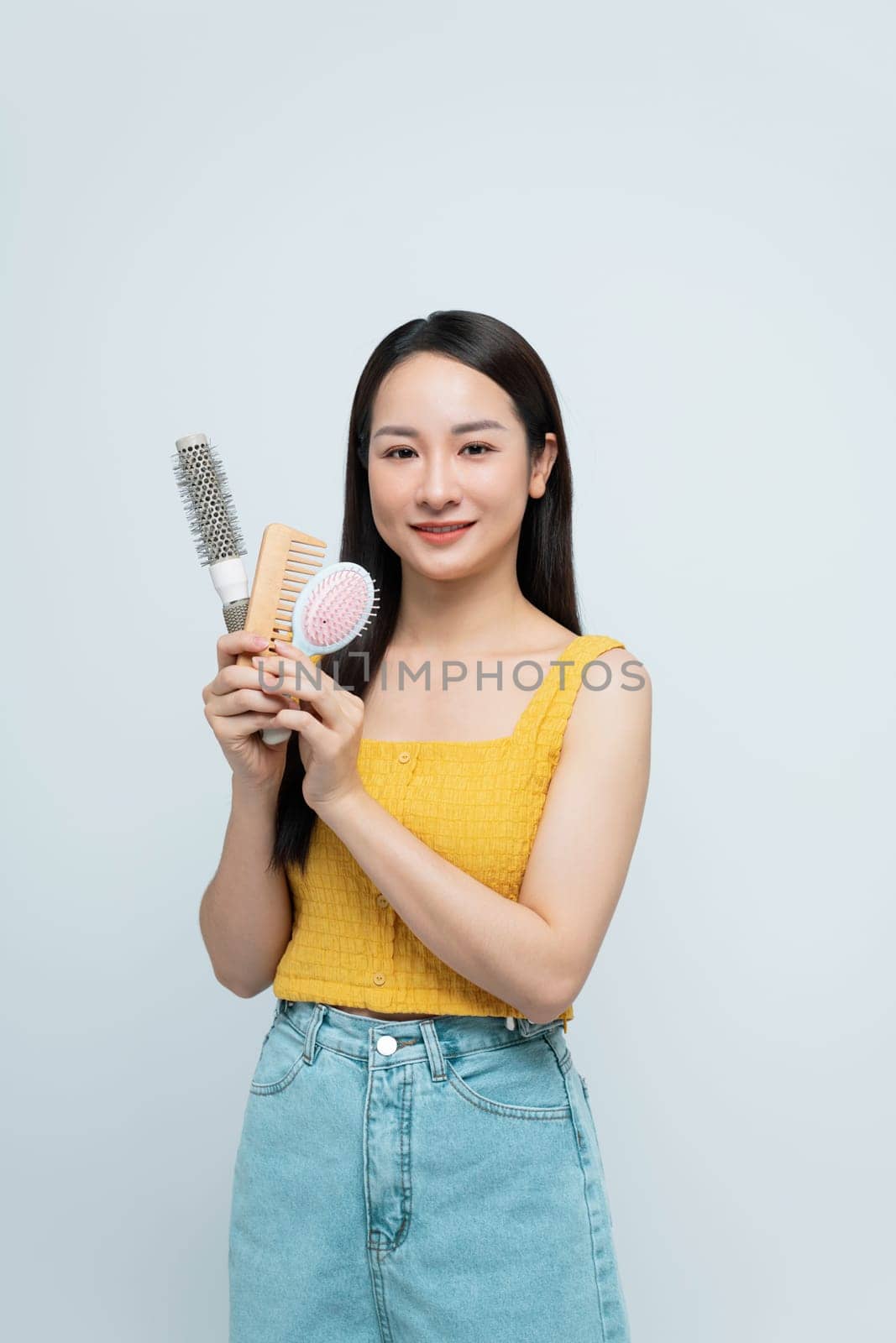 Smiling Woman Holding Hair Brushes And Combs On White Background