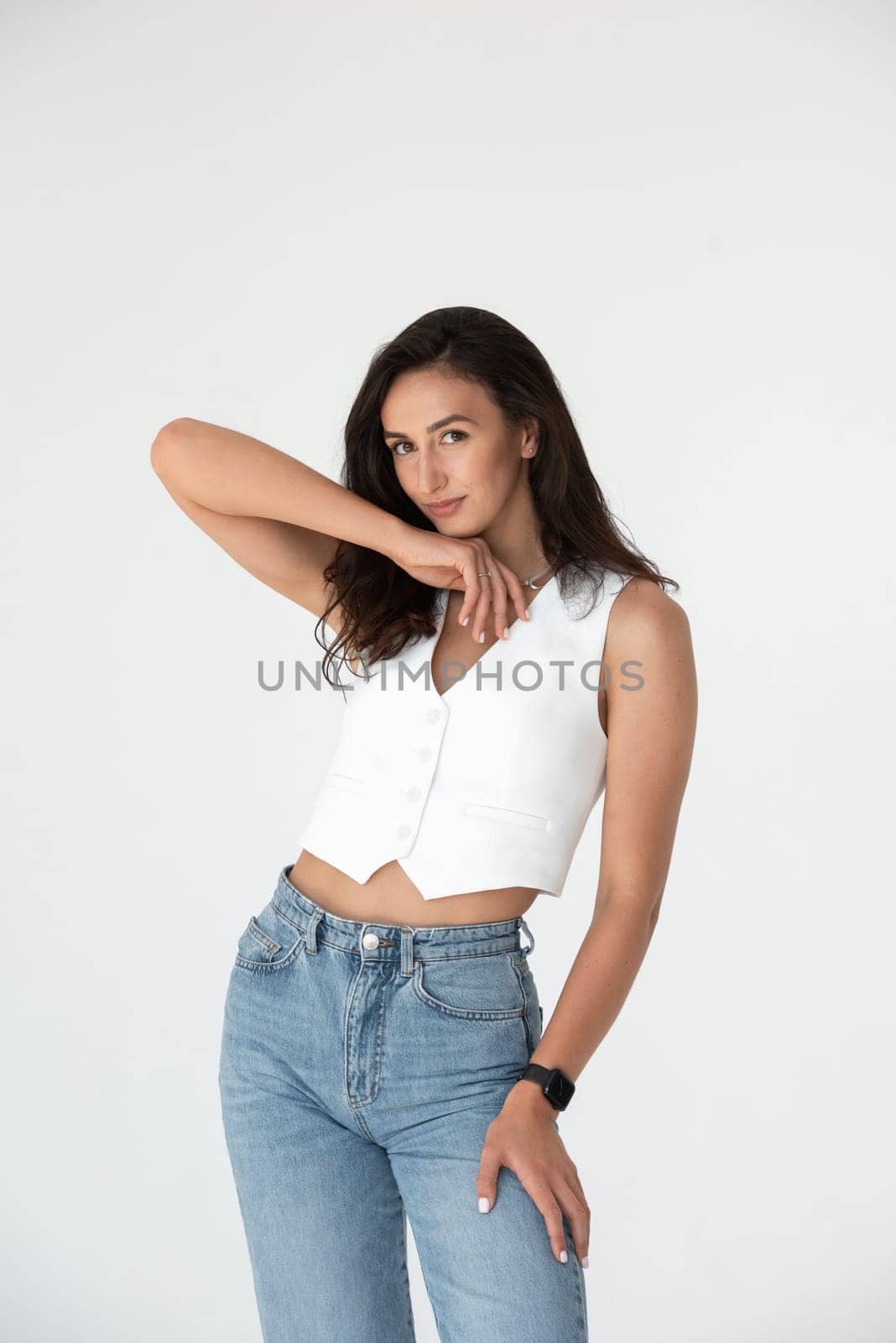 Happy beautiful girl posing in a new hot summer look. Wearing blue jeans and white waistcoat.