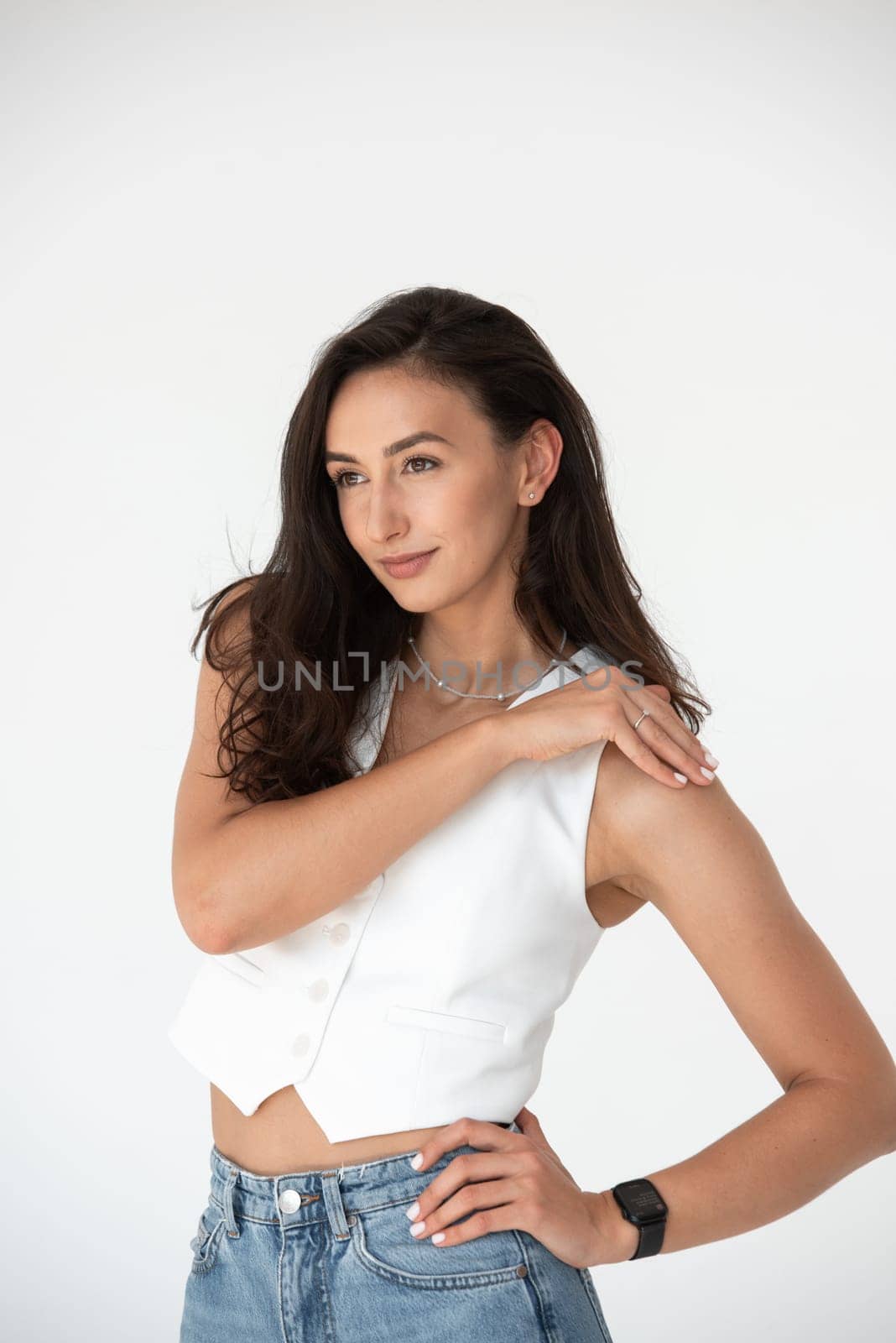 Happy beautiful girl posing in a new hot summer look. Wearing blue jeans and white waistcoat.