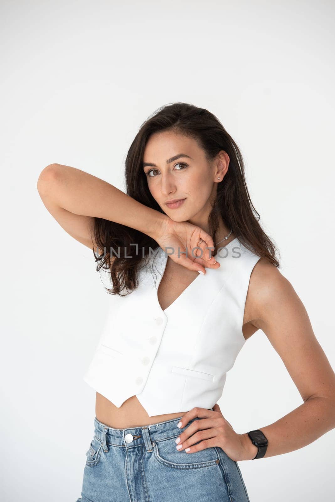 Happy beautiful girl posing in a new hot summer look. Wearing blue jeans and white waistcoat.
