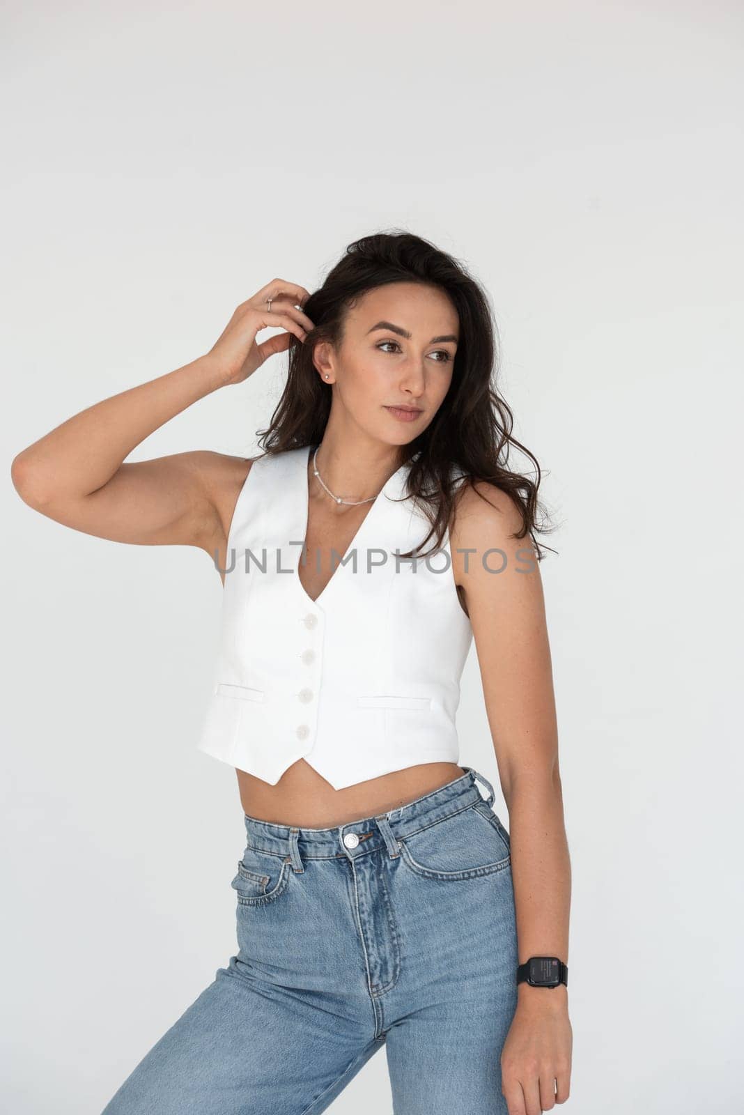 Happy beautiful girl posing in a new hot summer look. Wearing blue jeans and white waistcoat.