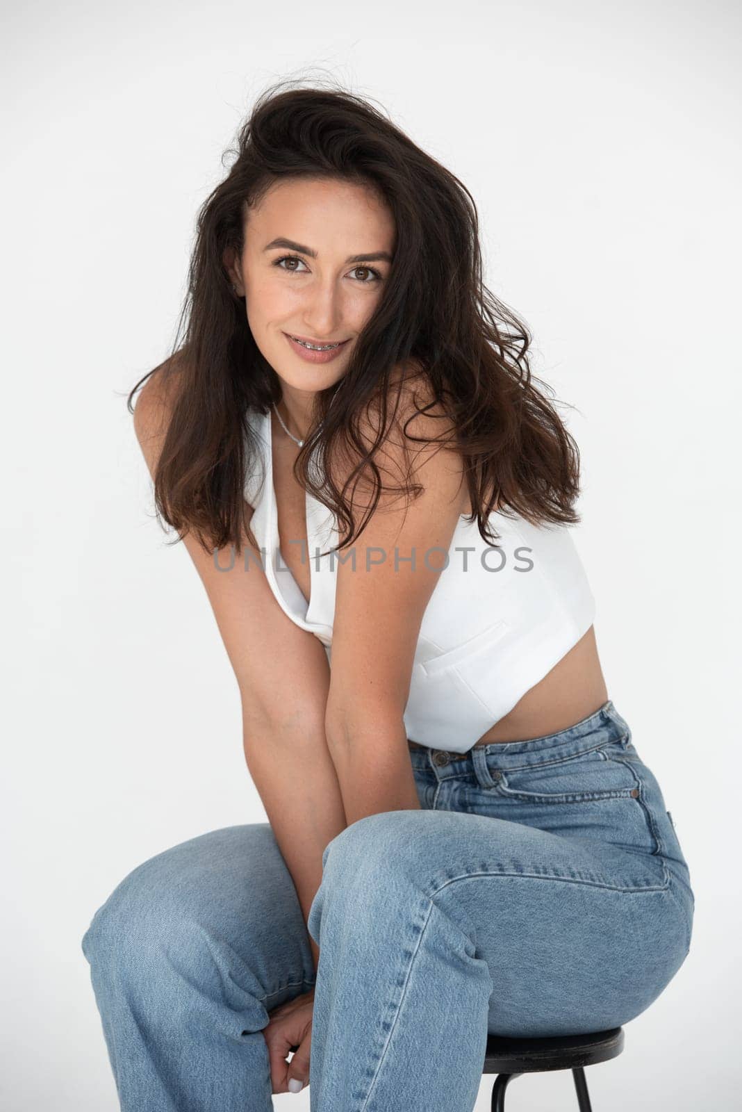 Happy beautiful girl posing in a new hot summer look. Wearing blue jeans and white waistcoat.