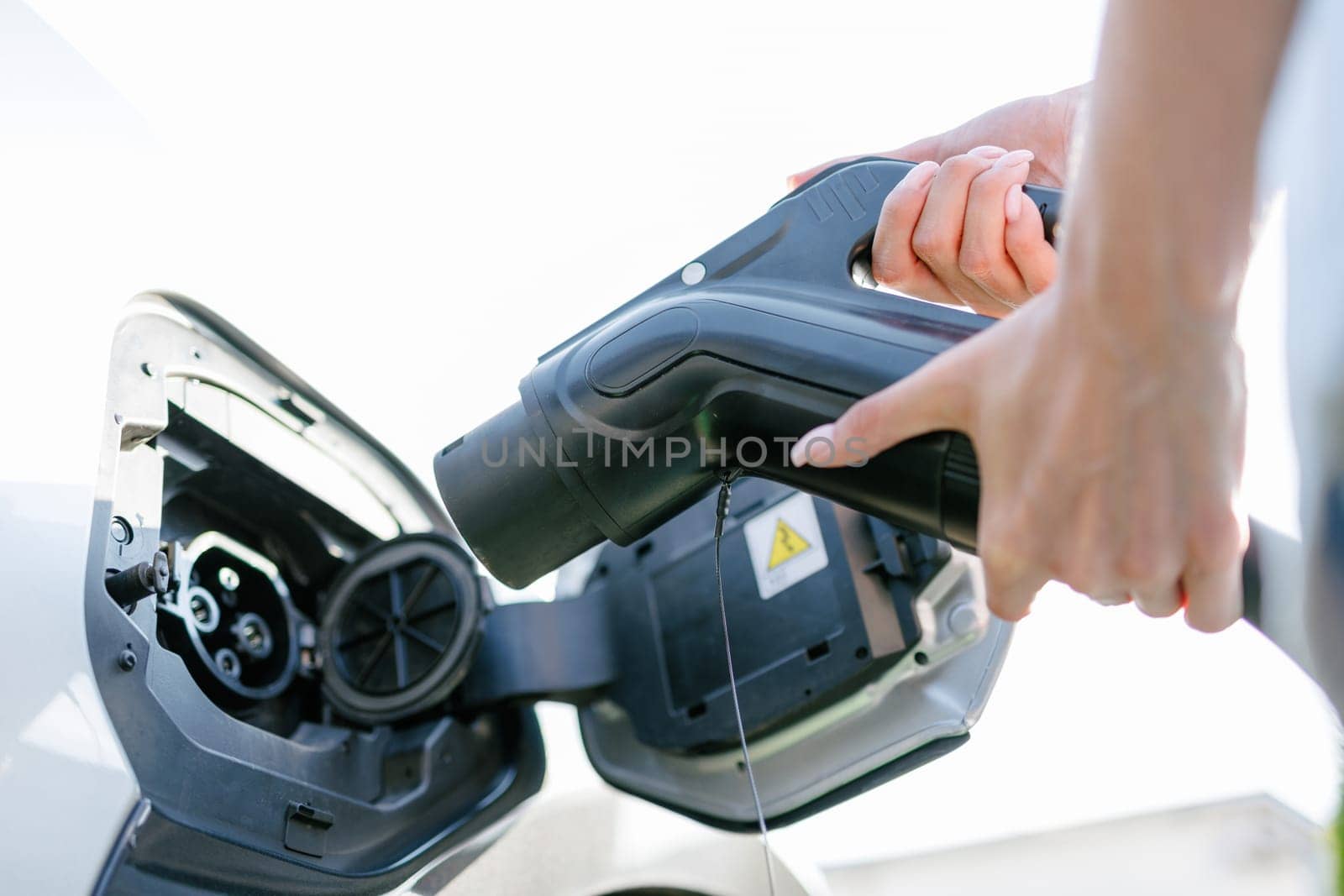 a girl charges her electric car at a charging station, Environmentally friendly energy sources, green energy concept, solar energy