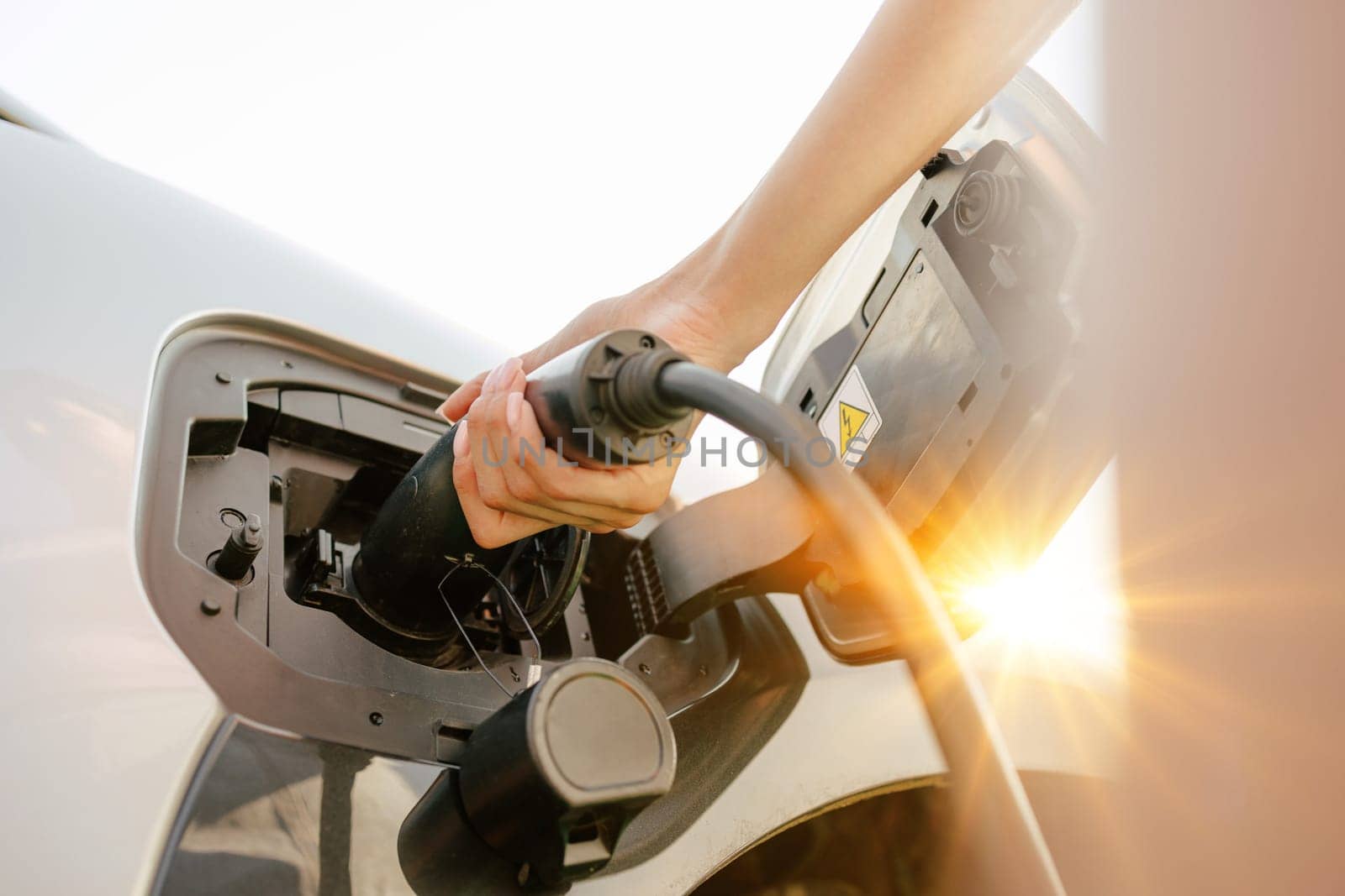 a girl charges her electric car at a charging station, Environmentally friendly energy sources, green energy concept, solar energy
