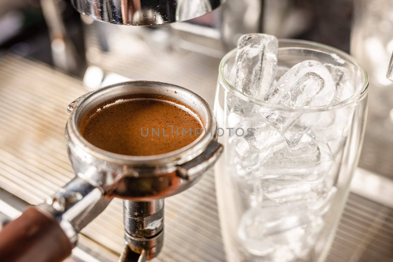 the barista's hand holds a cone with ground coffee near the coffee machine and prepares cold coffee, the barista prepares ice latte