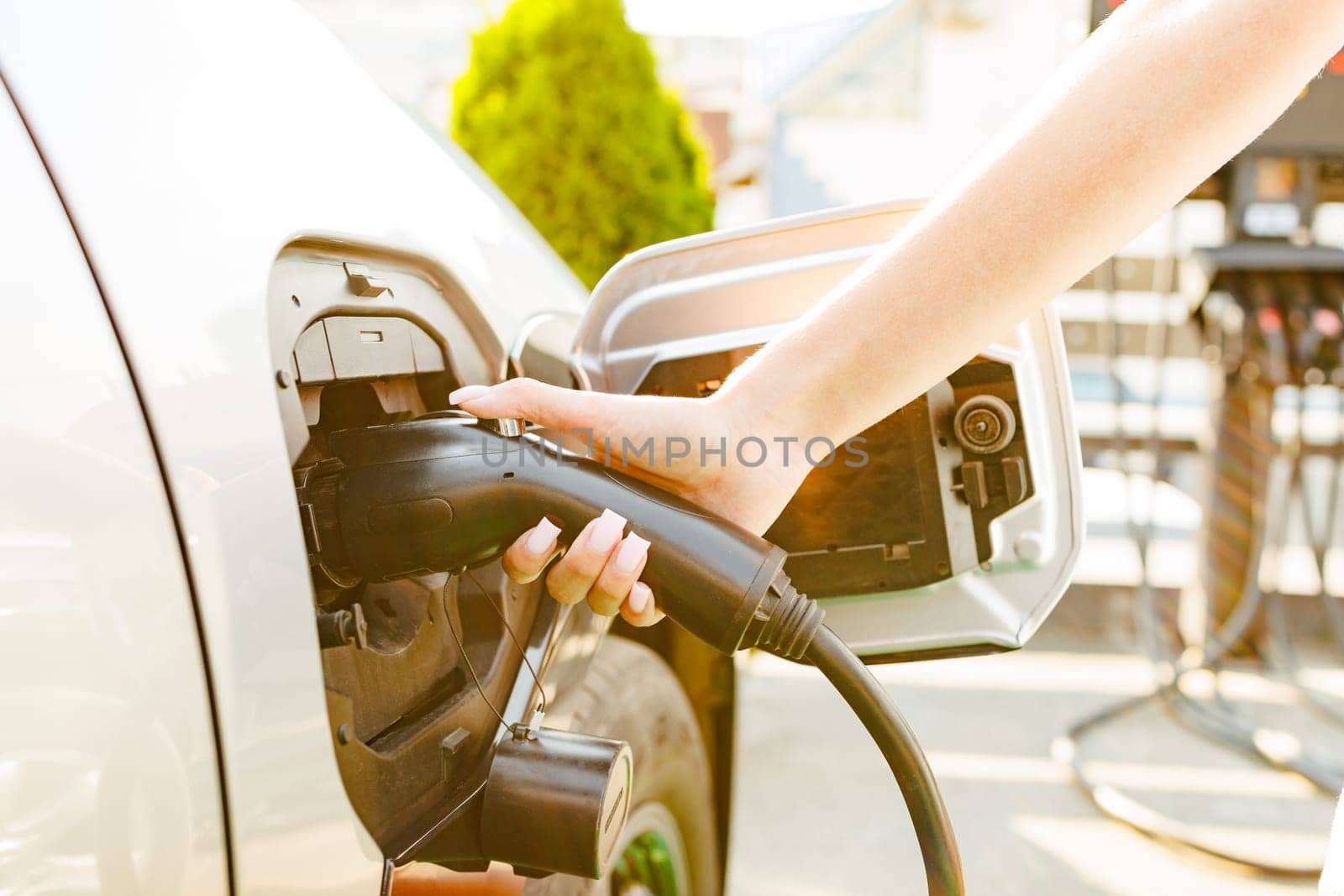 a girl charges her electric car at a charging station, Environmentally friendly energy sources, green energy concept, solar energy