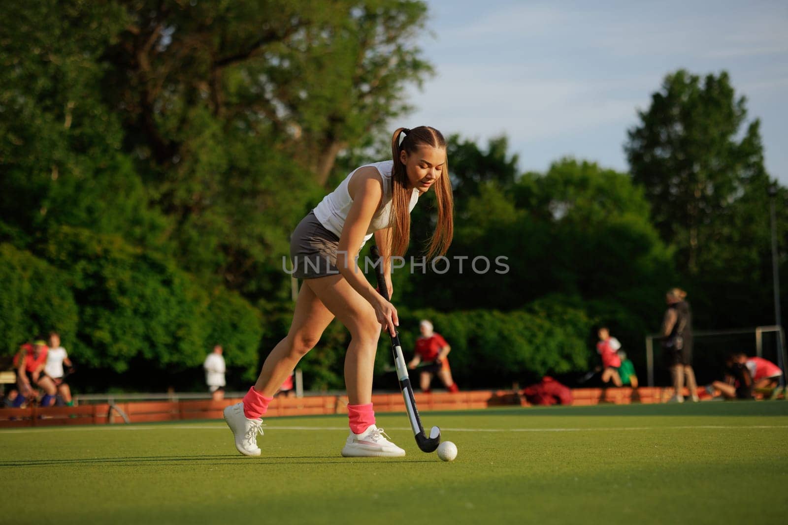 girl hockey player plays field hockey on a sunny day, female hockey player hits the ball with a stick, field hockey concept