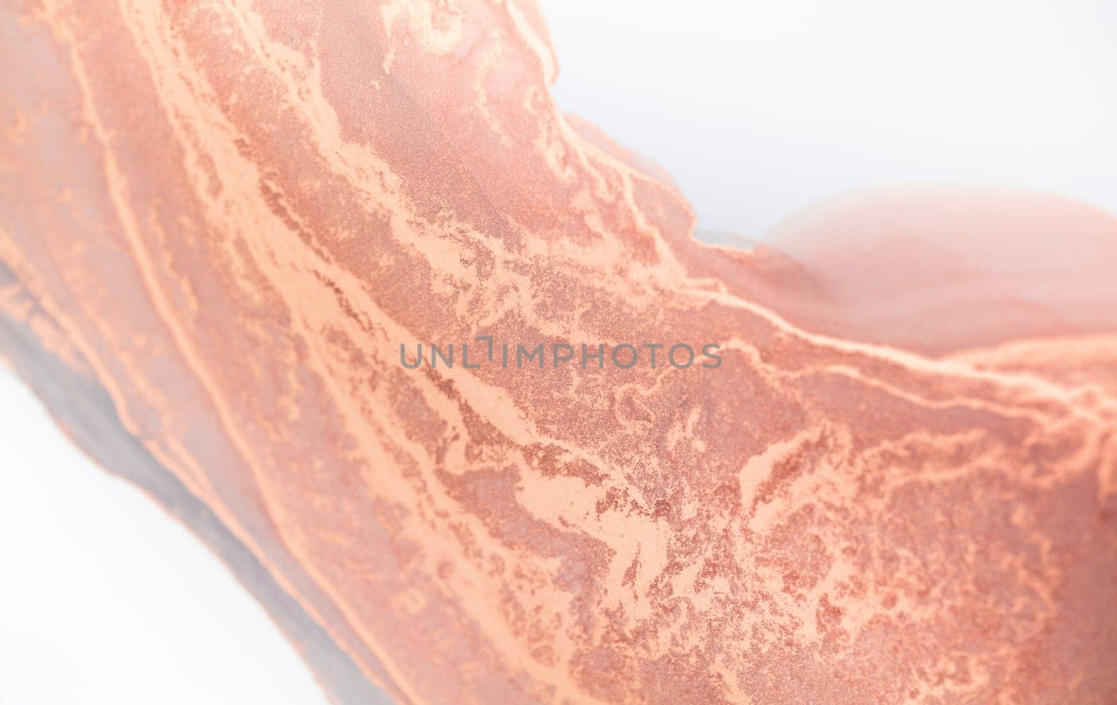 A close-up photo of copper paint swirling and blending with white, creating a smooth, abstract texture.