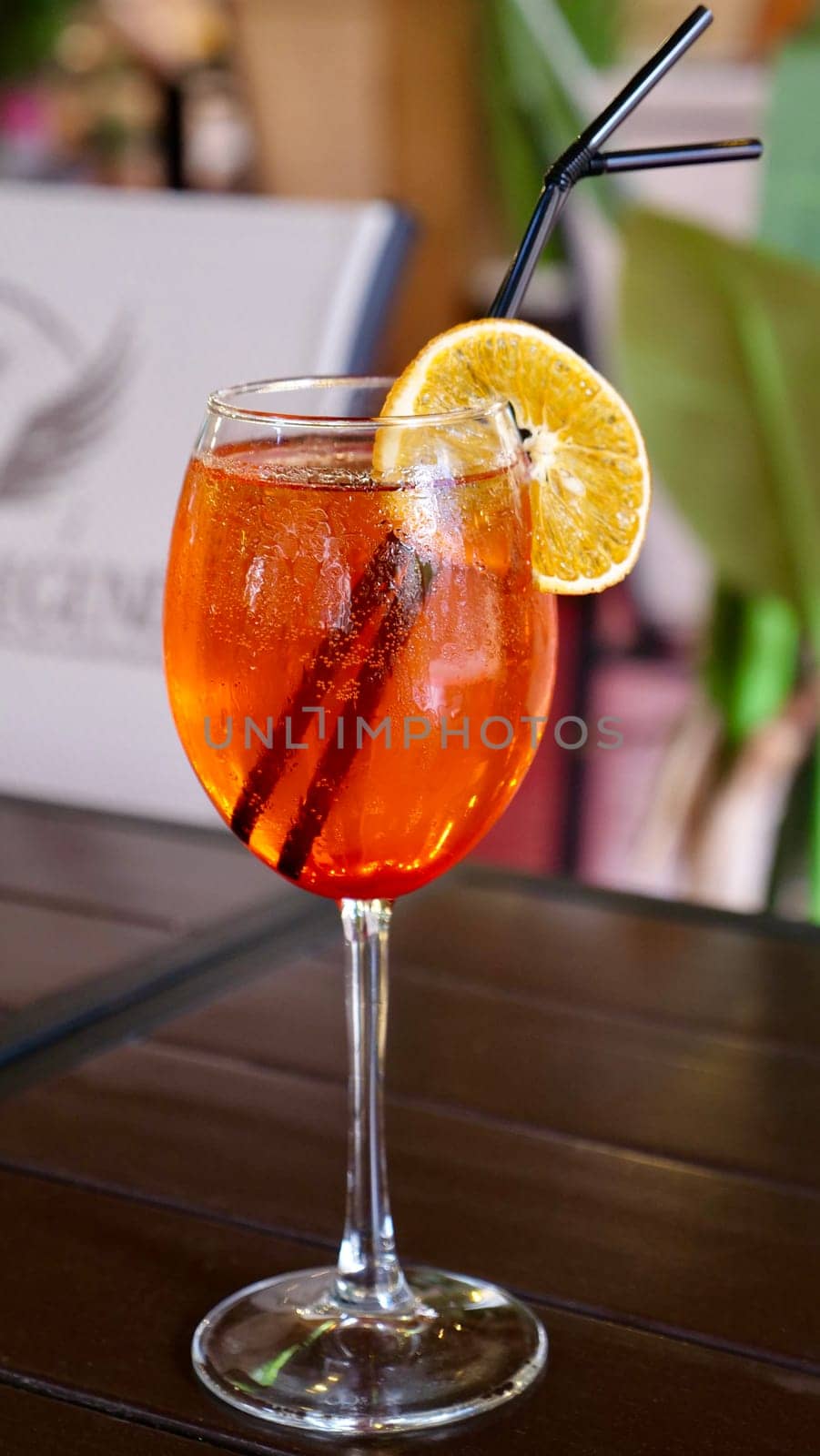Alcocolous orange cocktail aperol syringe in glass with orange slice in restaurant on table, close-up, vertical
