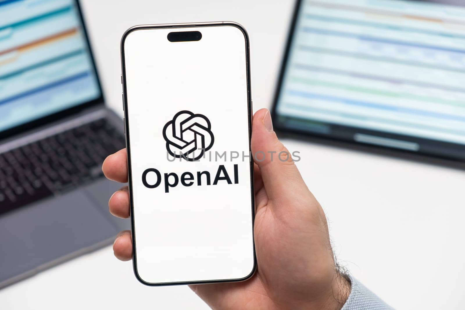 PRAGUE, CZECH REPUBLIC - JANUARY 21 2024: Open AI logo on the screen of smartphone in mans hand on the workplace background.