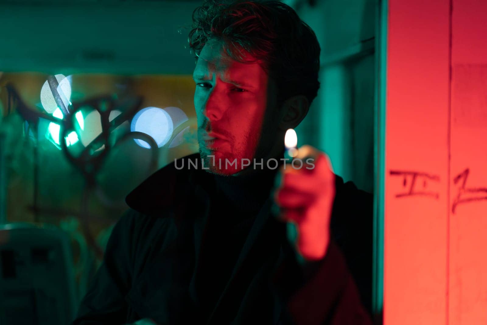 A man is smoking a cigarette in a telephone booth. The room is filled with a red and green glow, giving it a mysterious and eerie atmosphere. The man's face is obscured by the smoke