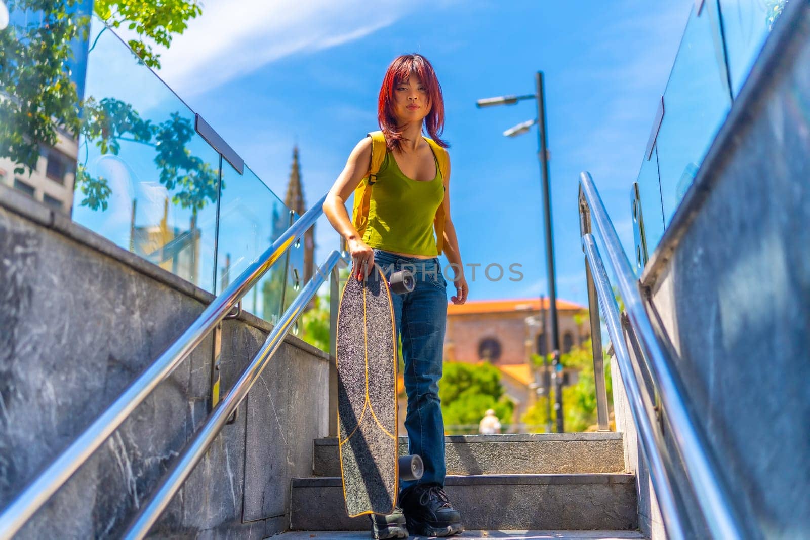 Urban portrait of a chinese young woman holding skateboard standing upstairs in the city