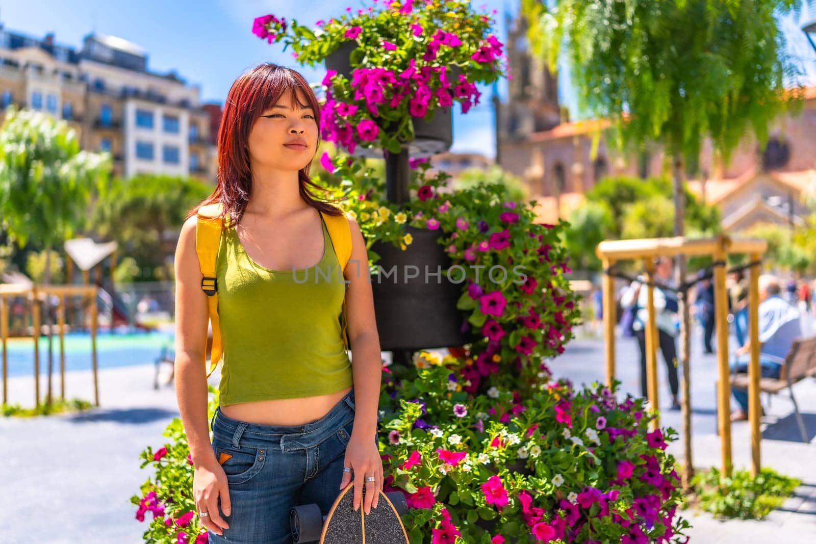 Portrait of a female young asian skater smiling standing on square with flowers