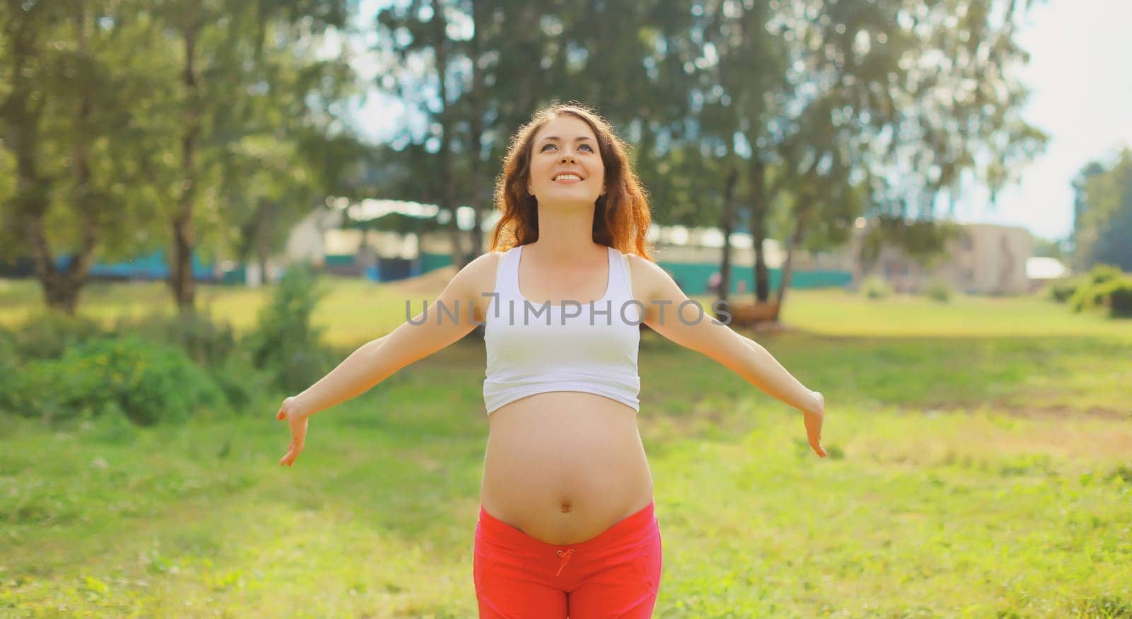 Maternity, pregnancy, happy young pregnant woman enjoying warm sunny day in summer park