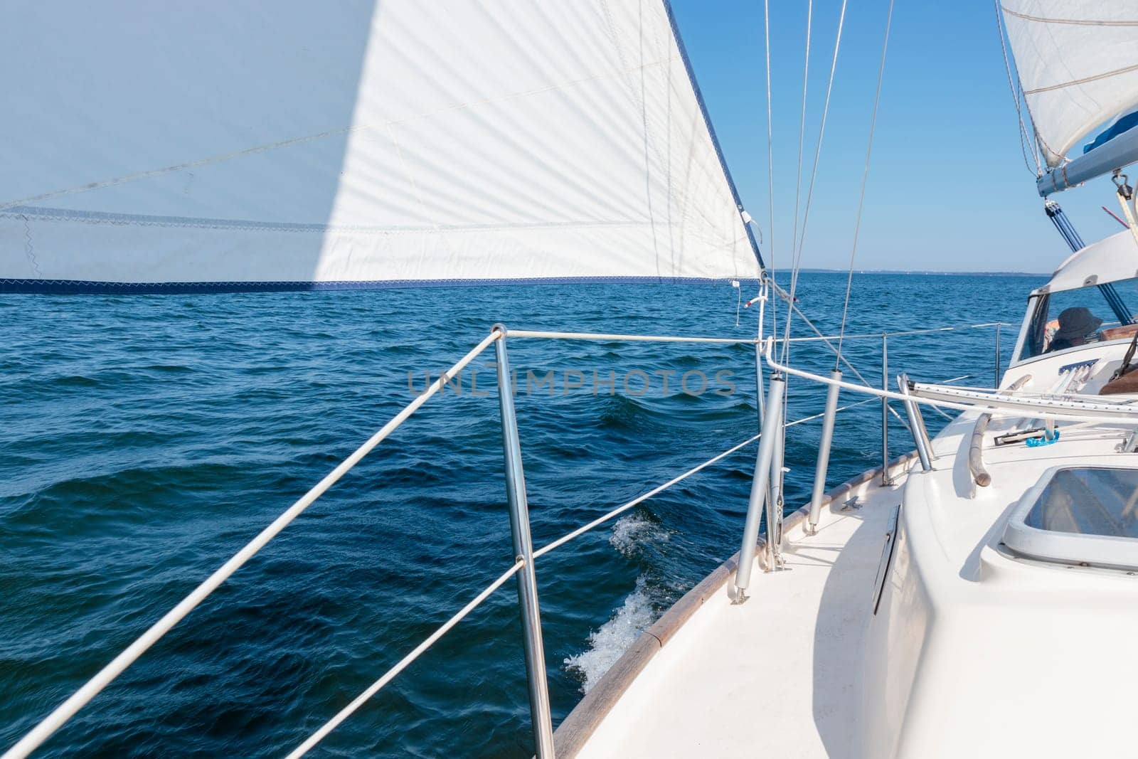 Luxury cruise on a sailing rigged yacht under a genoa and mainsail sailing in a light wind during the regatta. Yachting as a luxury sport and great vacation. View from the deck to the bow, mast, sails. Gulf of Finland