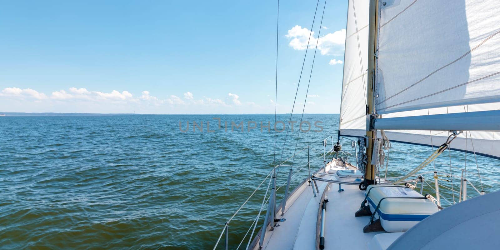 Luxury cruise on a sailing rigged yacht under a genoa and mainsail sailing in a light wind during the regatta. Yachting, sport, vacation. View from the deck to the bow, mast, sails. Banner, Gulf of Finland