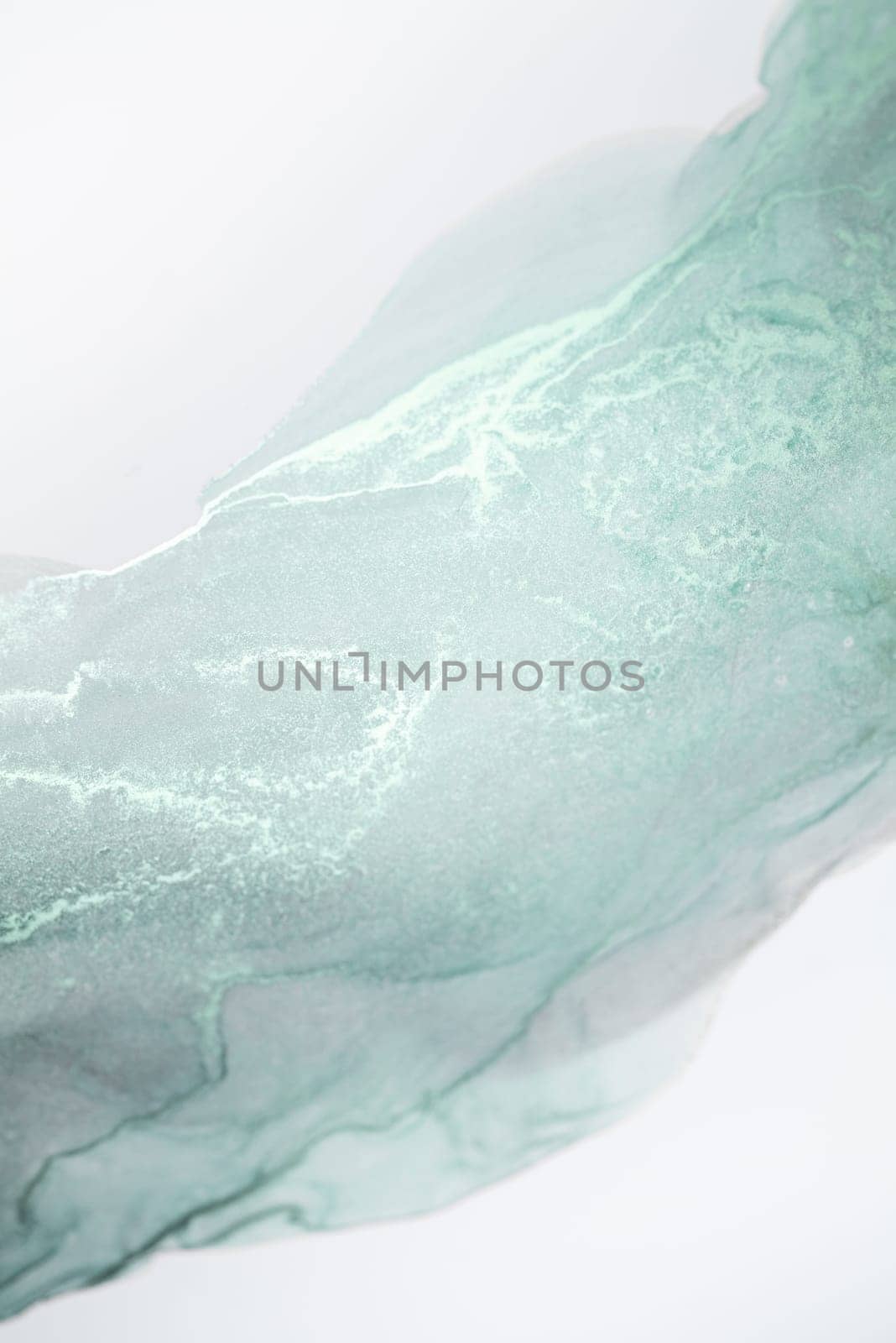 A close-up photograph of a light mint green ink swirl on a white background.