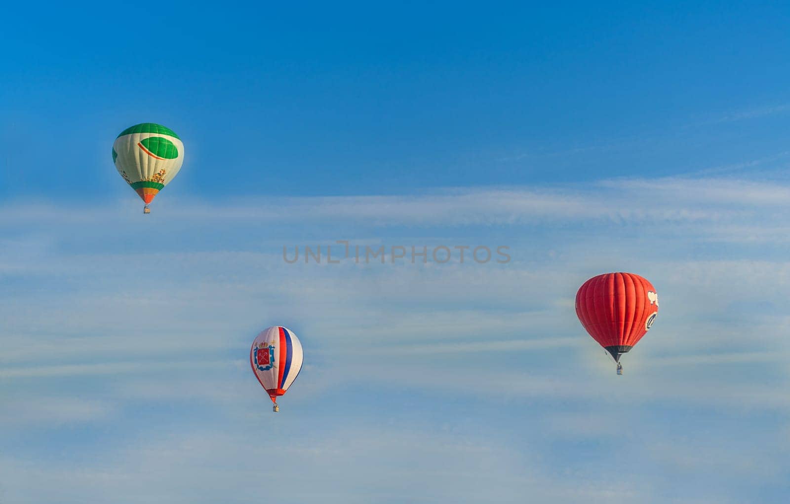 Balloons of different colors soar in the blue sky with light clouds, Belarus, Minsk, Europe
