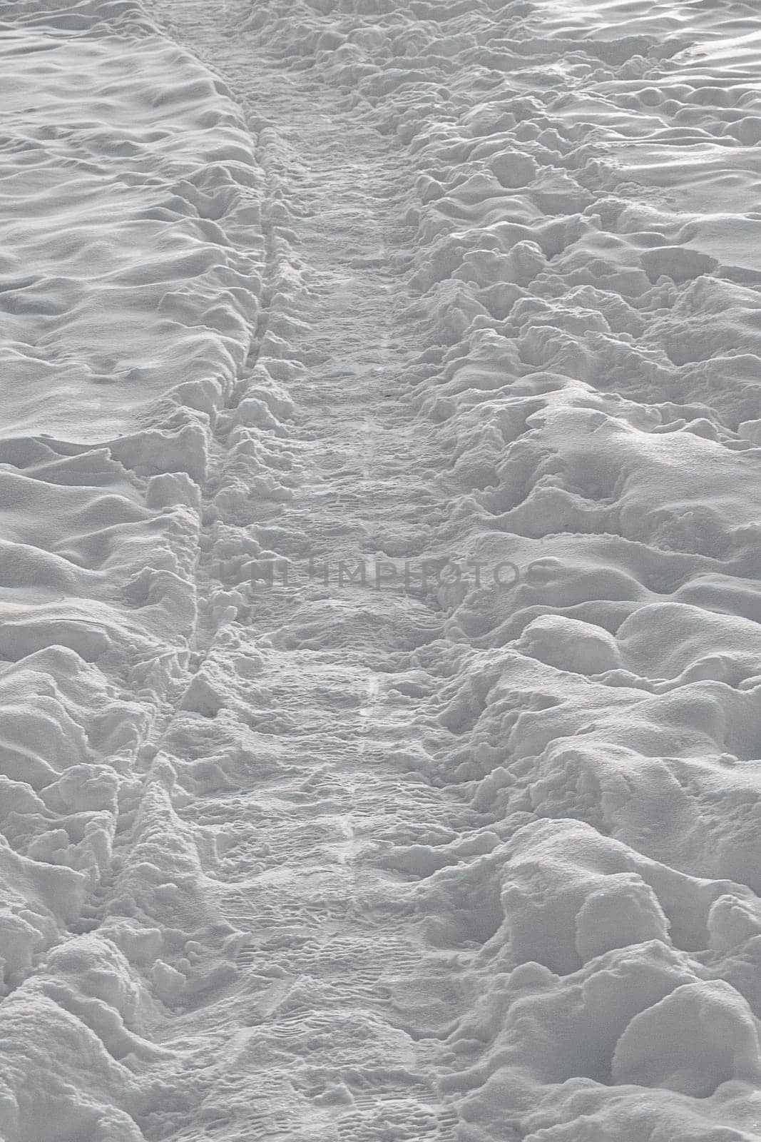 Path and footprints on the snow surface in the evening.