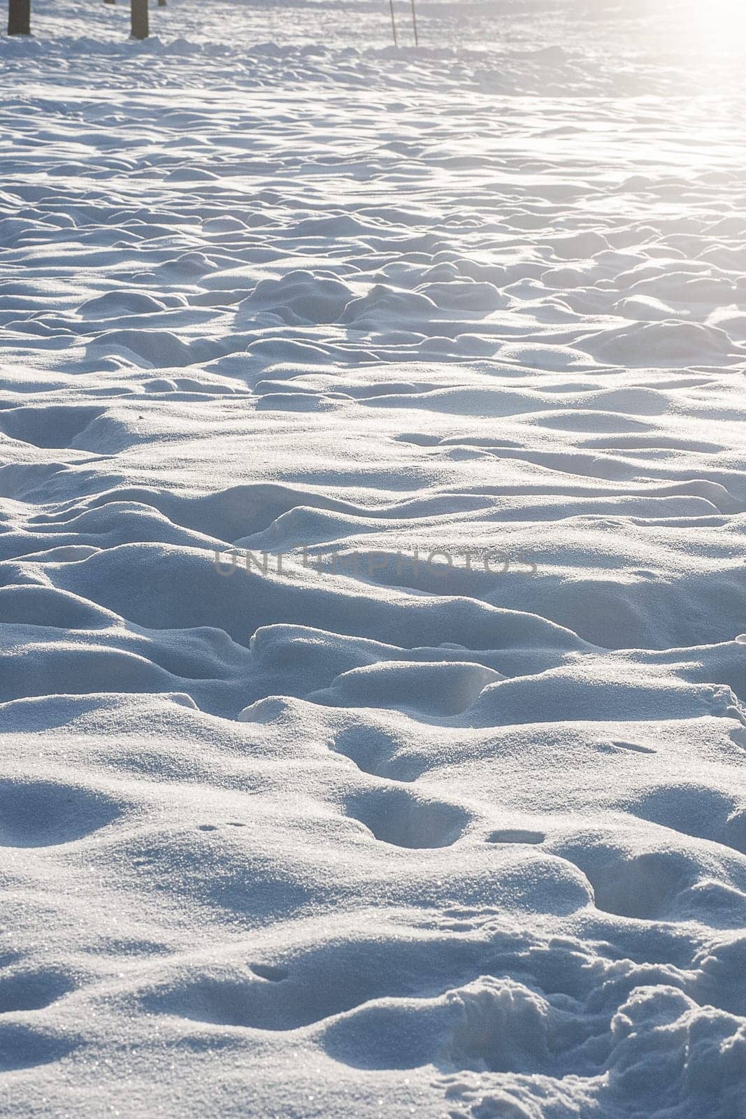 Sun glare, light on the snow. Scenic view of snow covered land. Brightly lit snow surface with footprints.