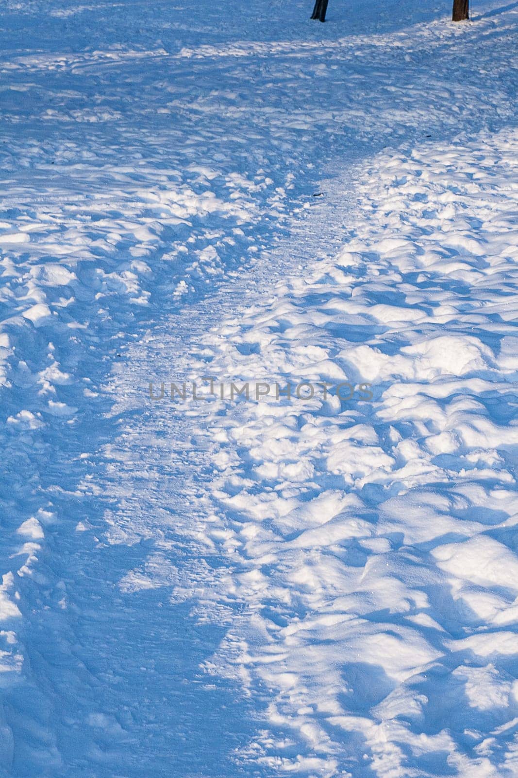 Footprints, path, shadows on the snow surface.