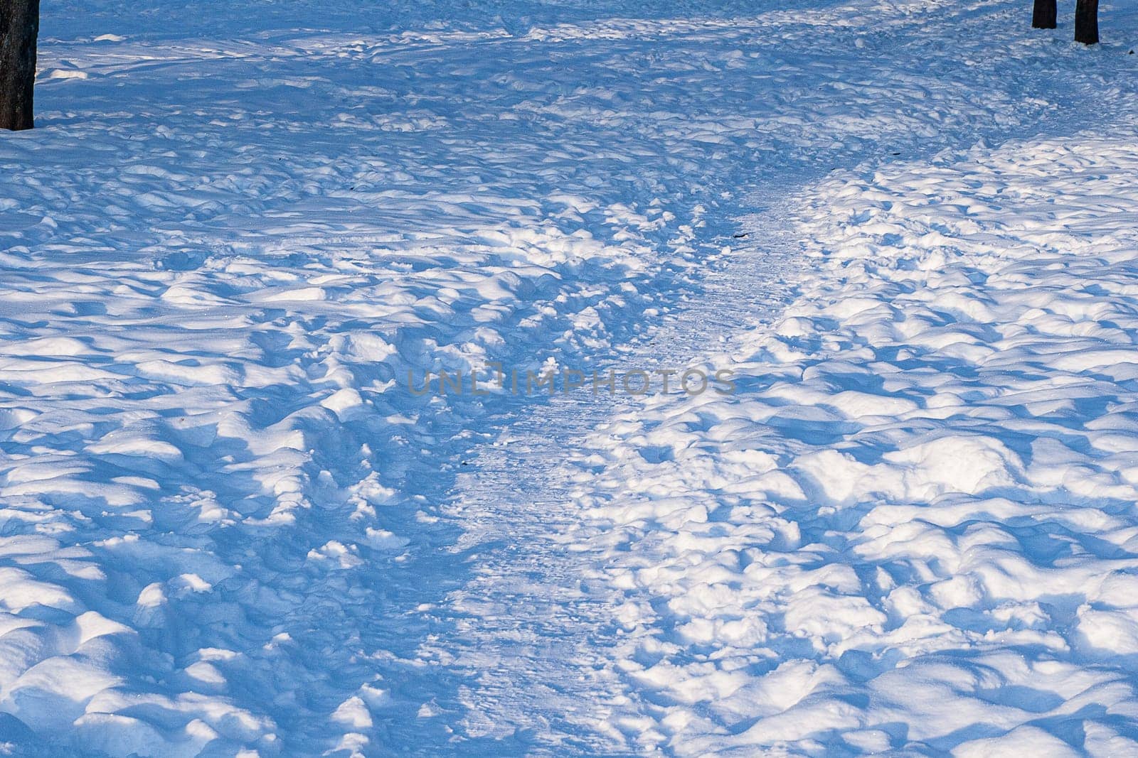 Footprints, path, shadows on the snow surface.