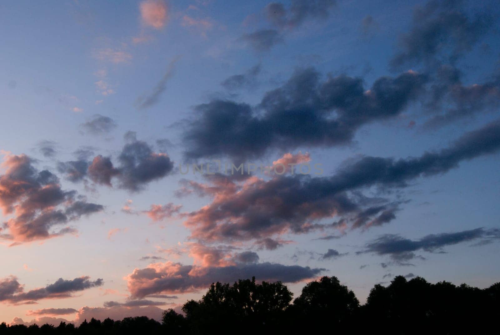 A view of a beautiful sunset with pink and gray clouds against a blue sky.
