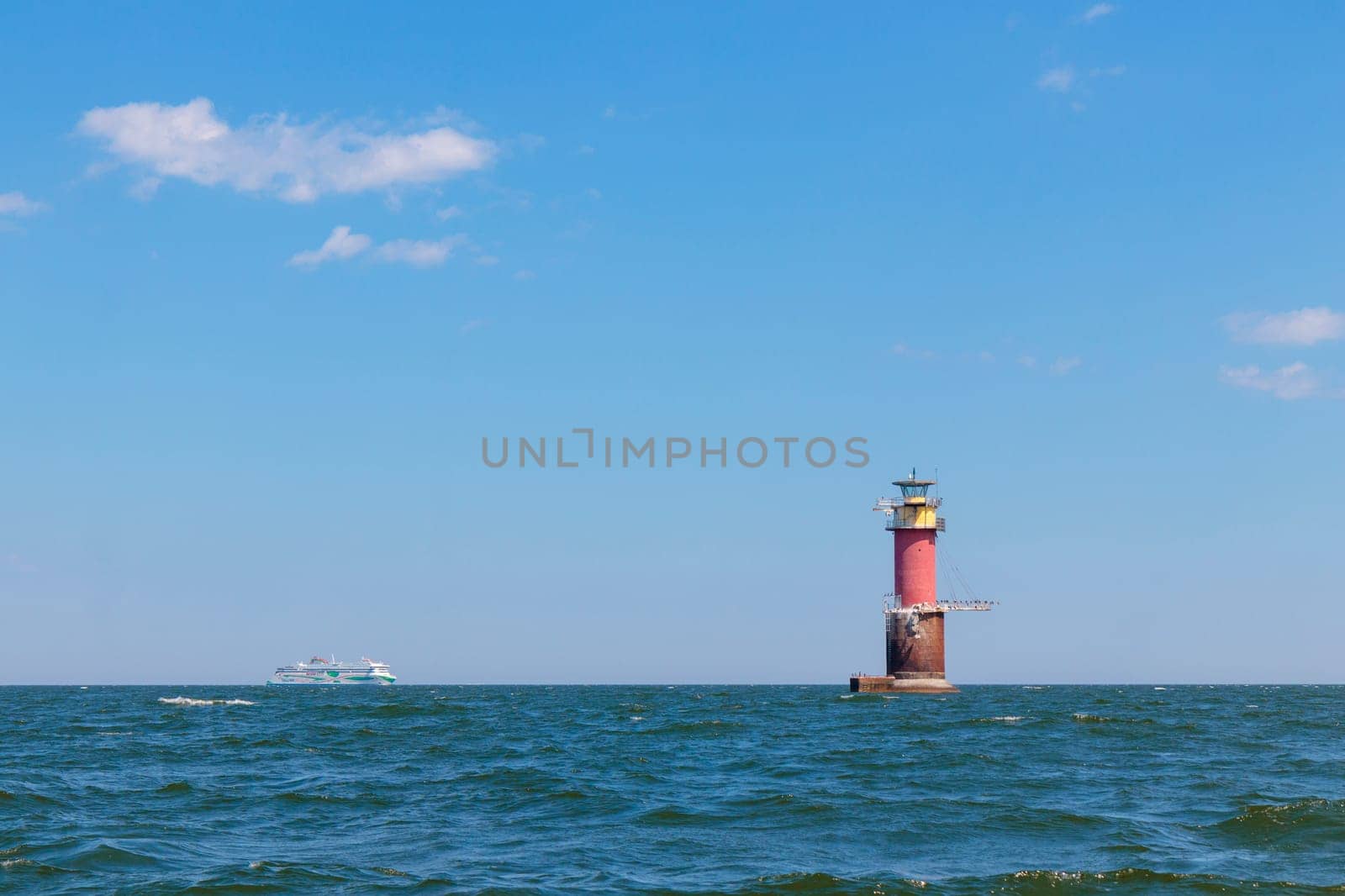 Gulf of Finland, Estonia, June 28, 2024 -A lighthouse in the Baltic Sea near Tallinn and ferry Tallink from Helsinki. Blue sky, clouds, waves, sea. Banner with copy space