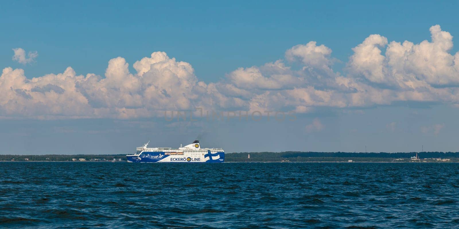 Gulf of Finland, Estonia, June 30, 2024 - Eckero line ferry boat Finlandia in Baltic sea on the horizon. Blue sky, clouds, waves, sea. Banner with copy space