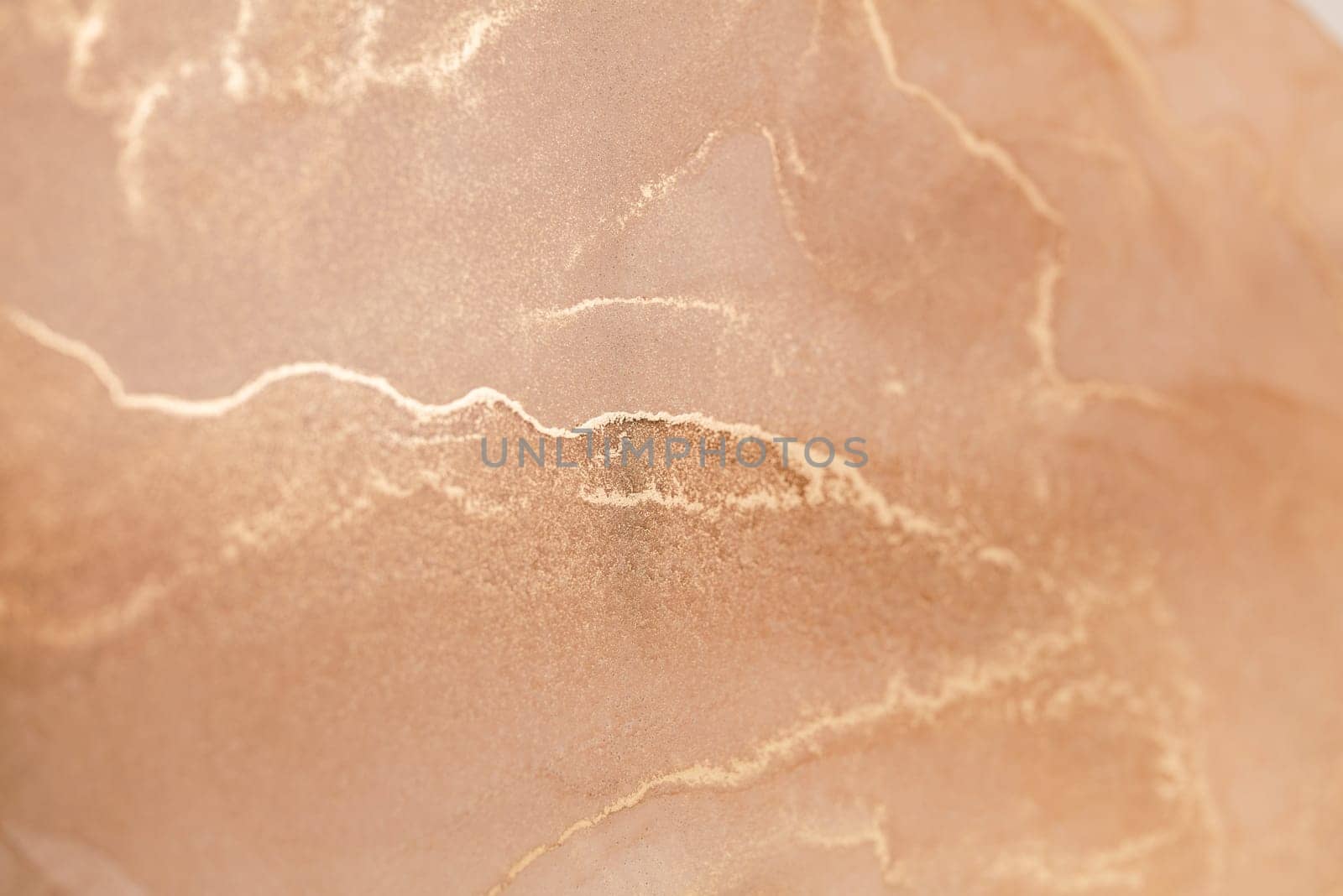 A close-up photograph showcasing a delicate abstract pattern of golden veins tracing across a soft, peachy background. This image evokes a sense of tranquility and warmth.